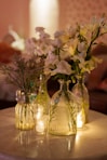 White flowers in vintage bottles on a table.