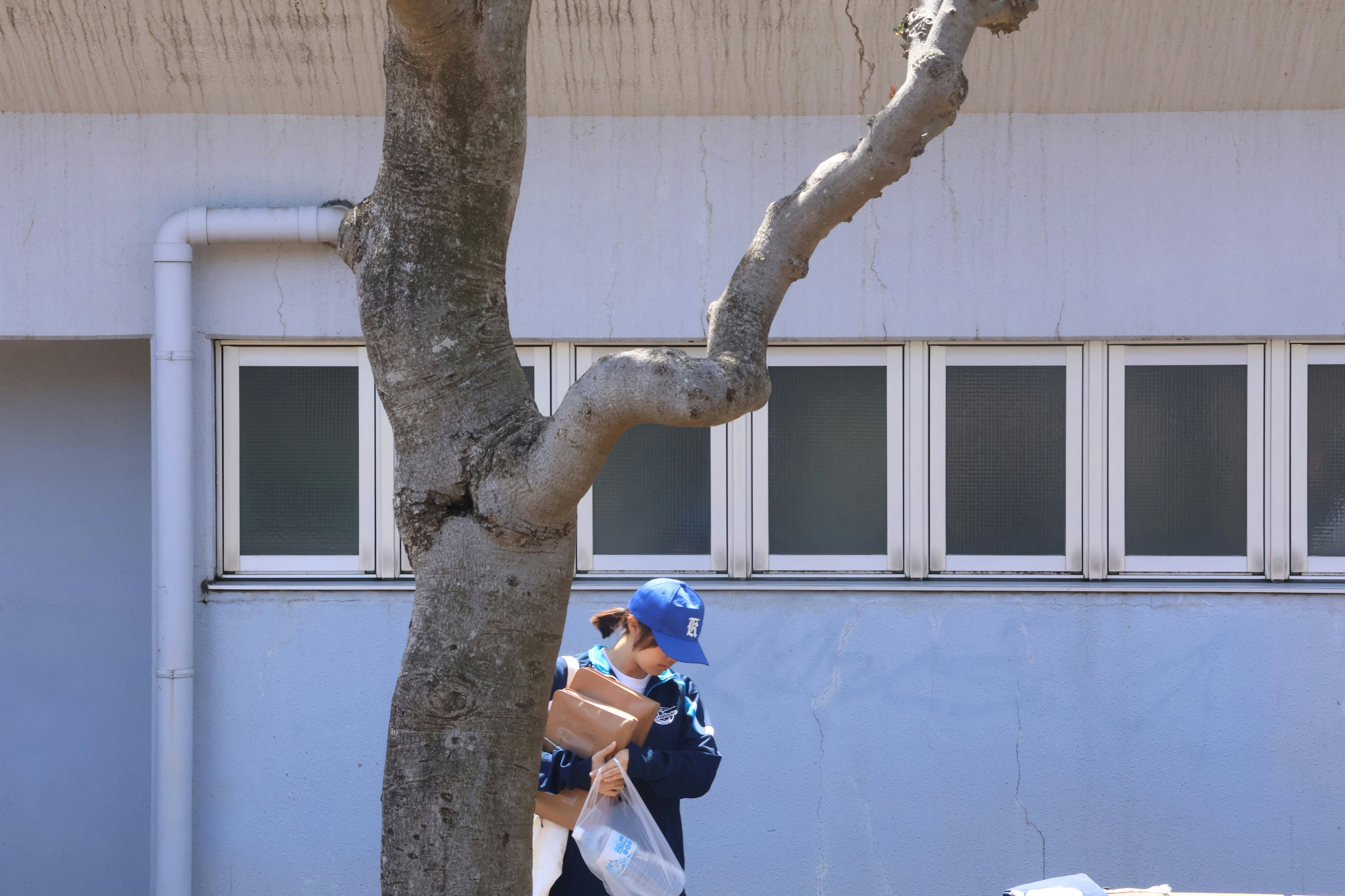 A child walks carrying packages near a building.