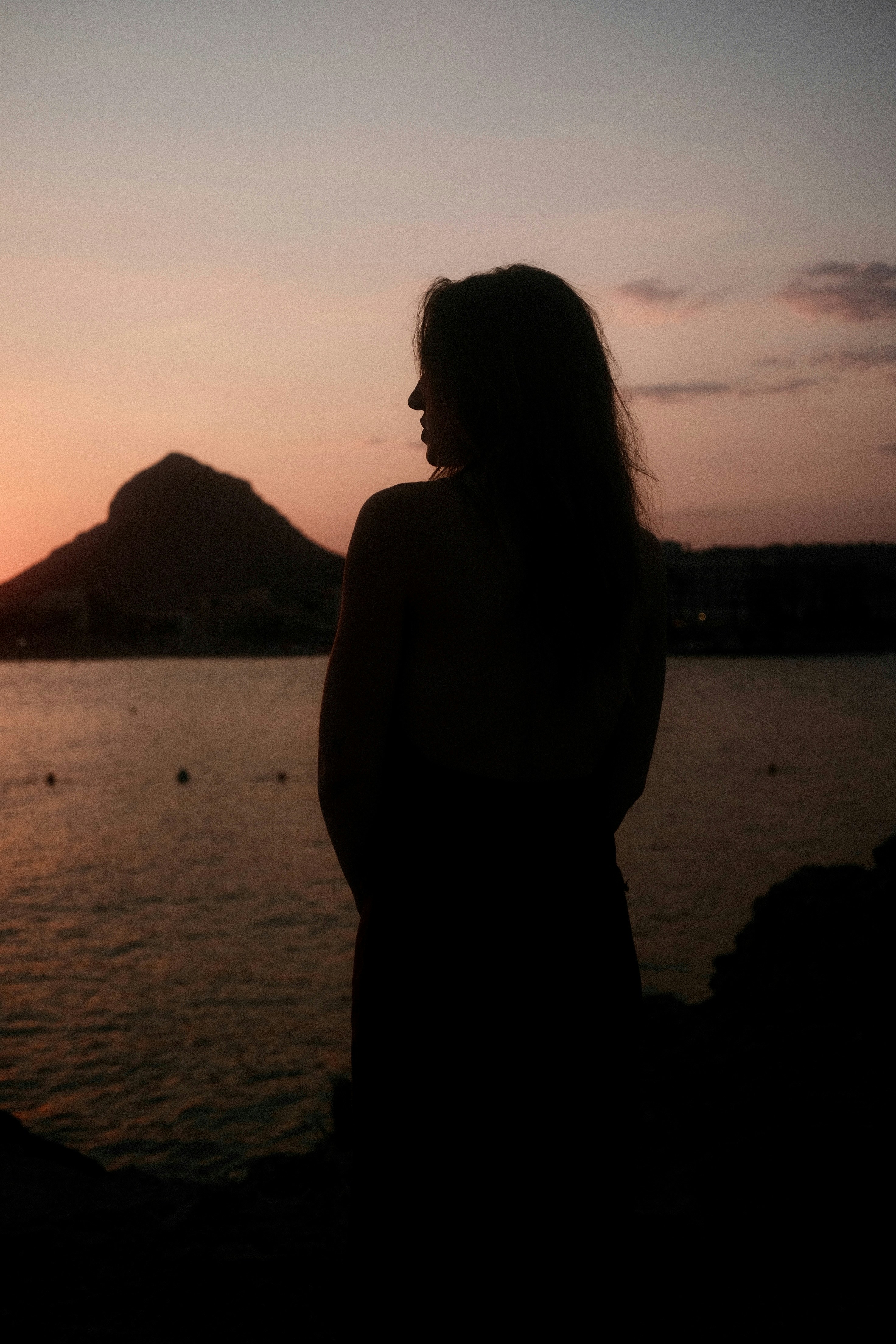 Silhouette of woman watching the sunset over the water.