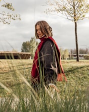 A woman in a red scarf walks outside.