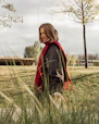 A woman in a red scarf walks outside.