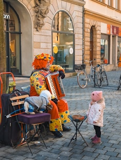 A clown plays the accordion for a child.