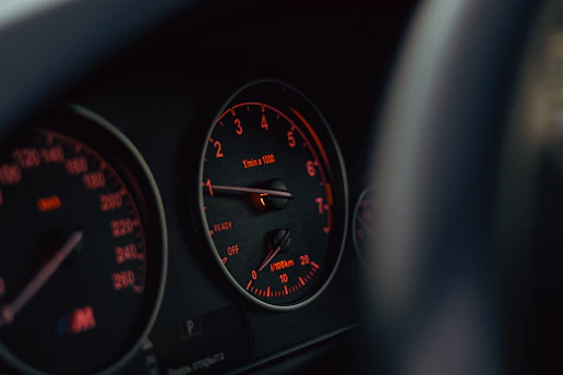 Car's dashboard with illuminated gauges displayed.