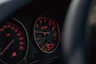 Car's dashboard with illuminated gauges displayed.