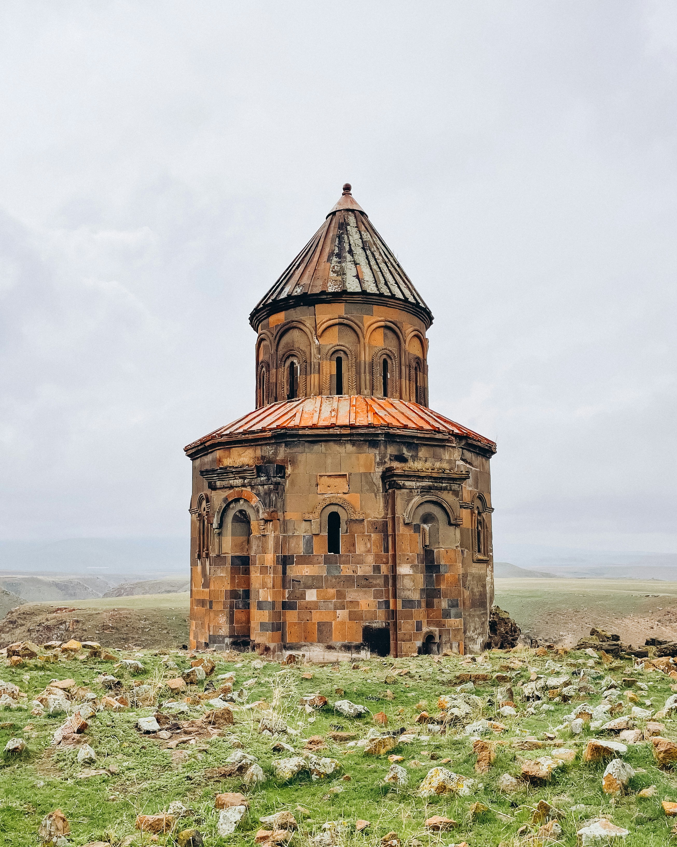 A stone church stands alone on grassy land.