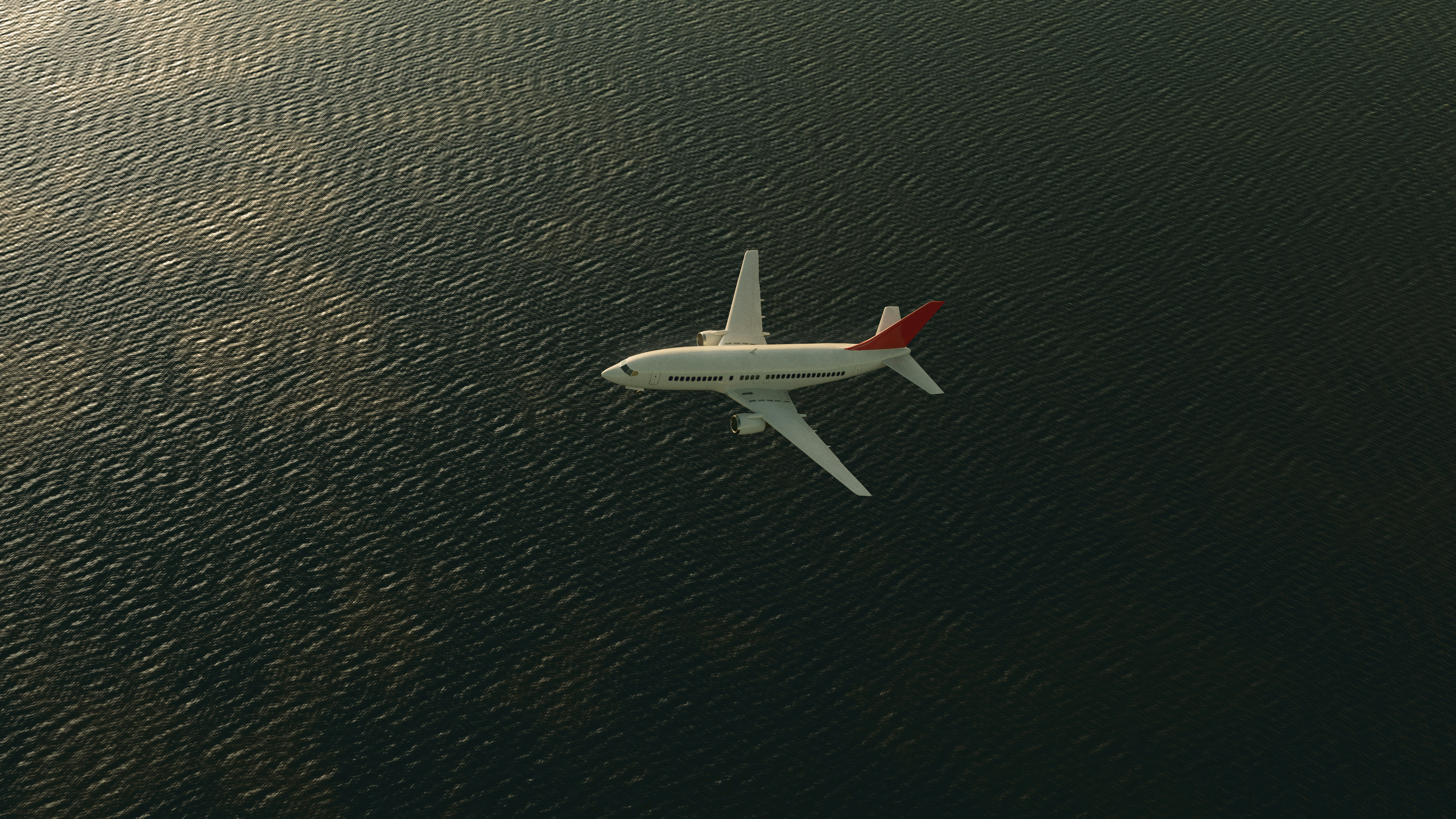 An airplane flies over a vast, dark sea.