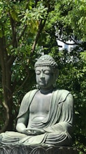 A serene buddha statue sits peacefully amidst lush greenery.
