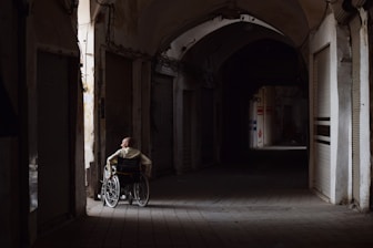 A person in a wheelchair looks down a dark hallway.