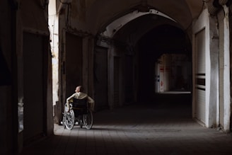 A person in a wheelchair looks down a dark hallway.