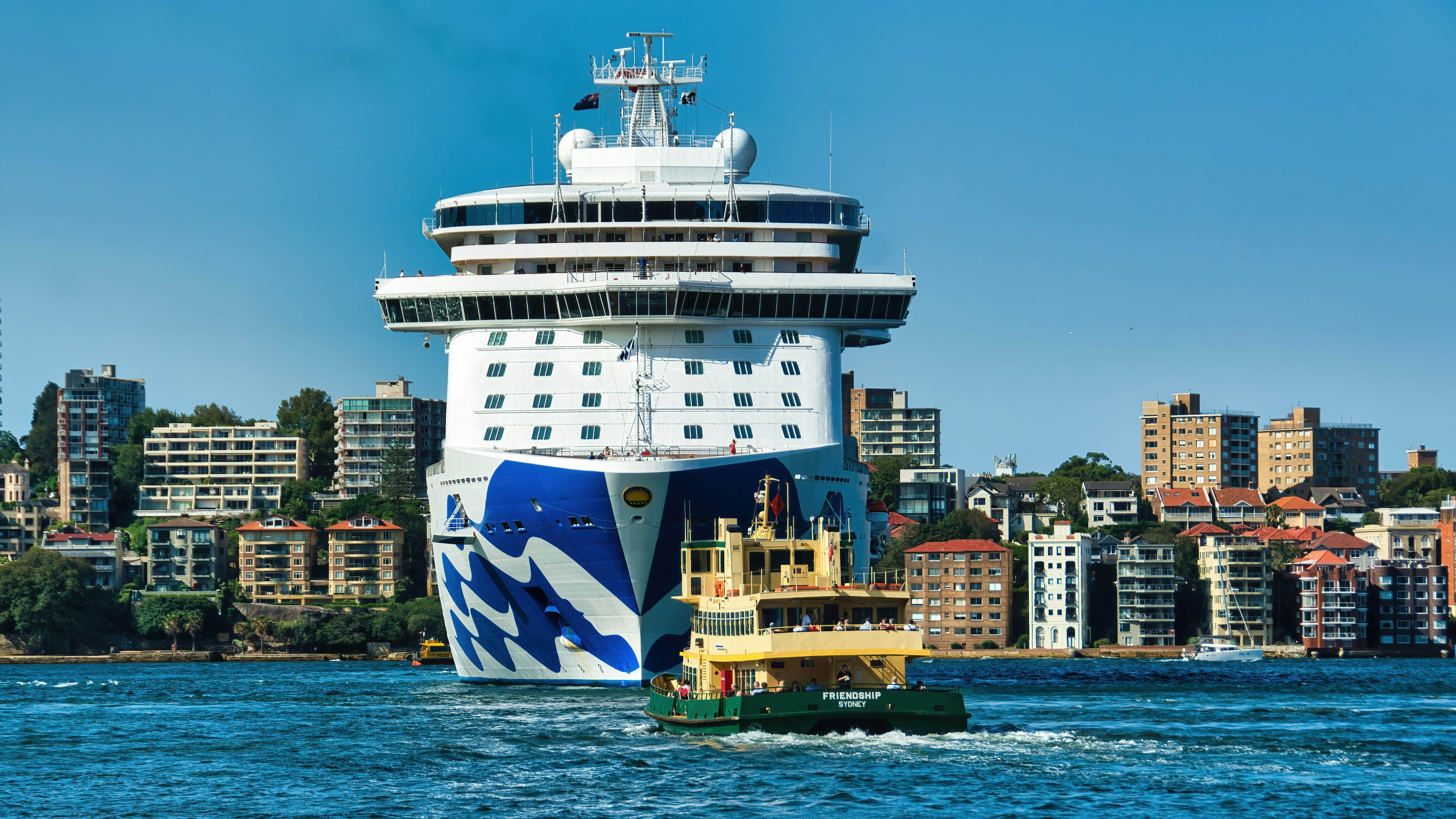 A large cruise ship sails near buildings.