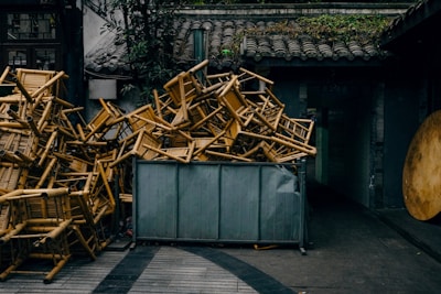 Chairs piled high in a metal container.