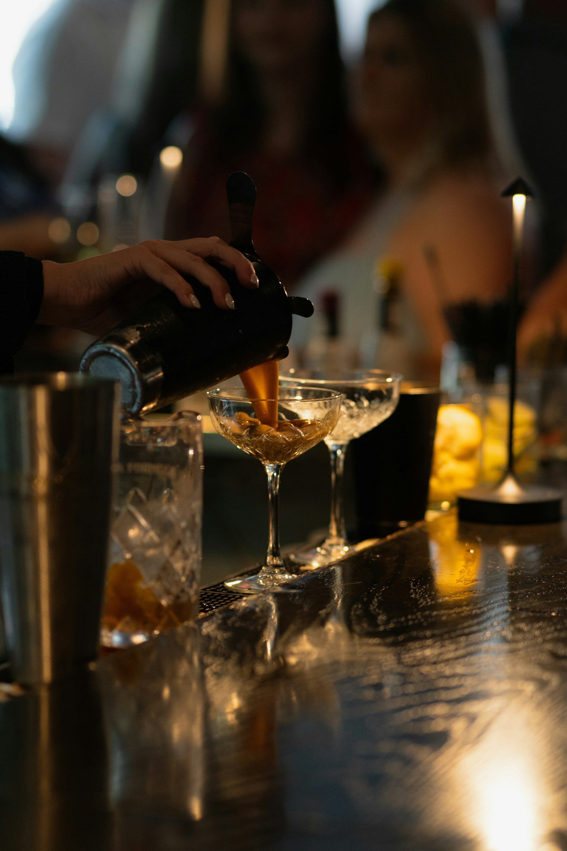 Bartender pouring drinks into champagne glasses.