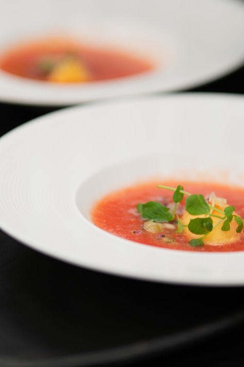 Tomato soup with garnish in white bowls.