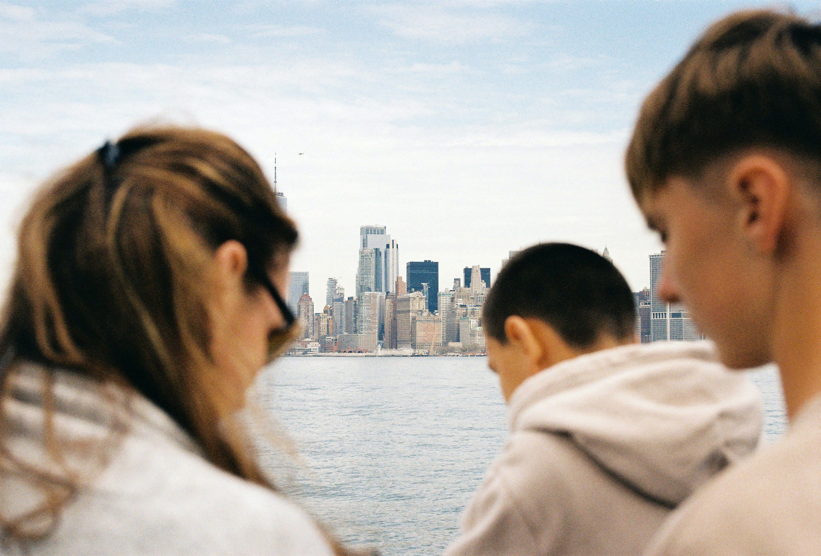 People gaze at a city skyline across the water.