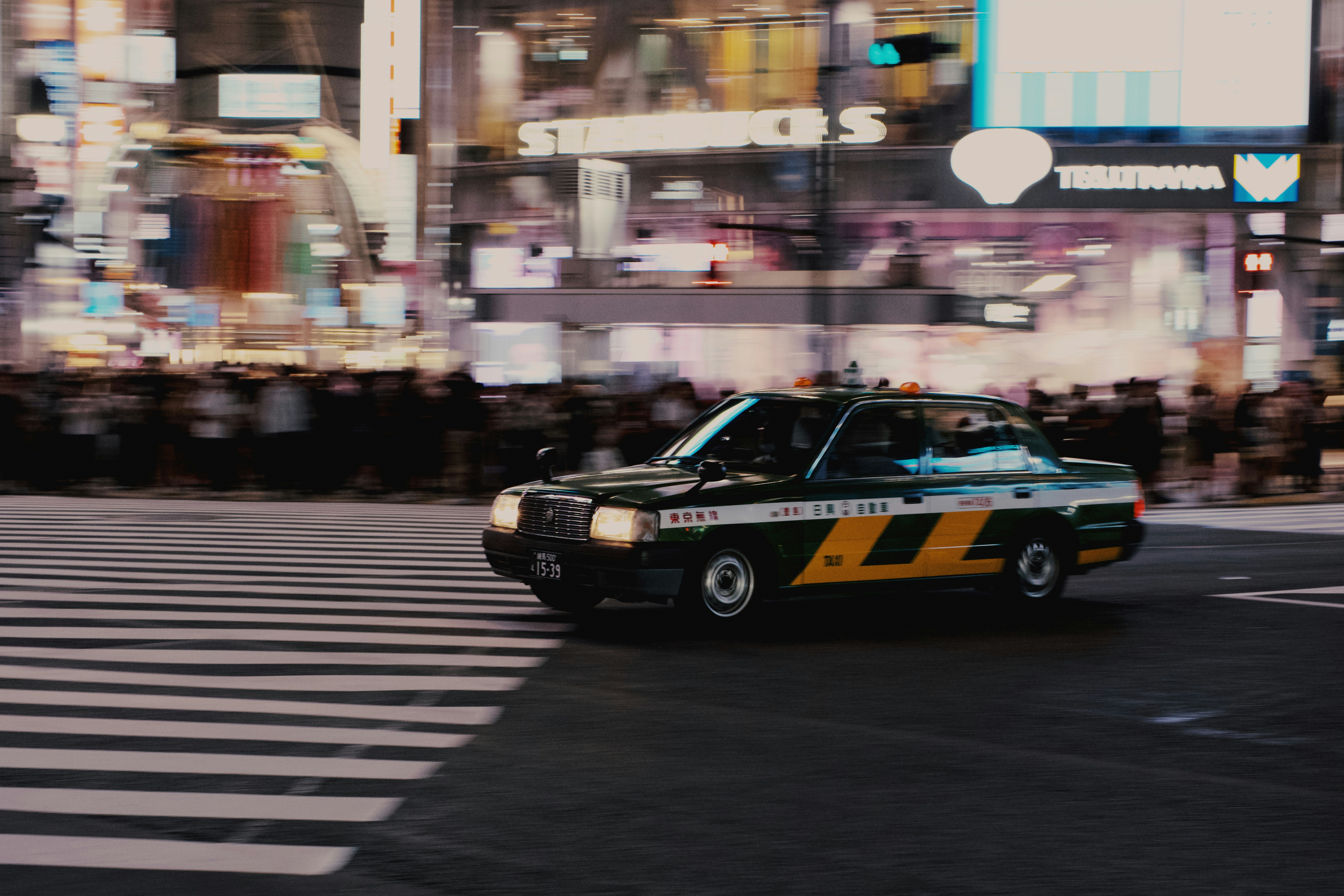 A taxi speeds through a busy, lit city street.
