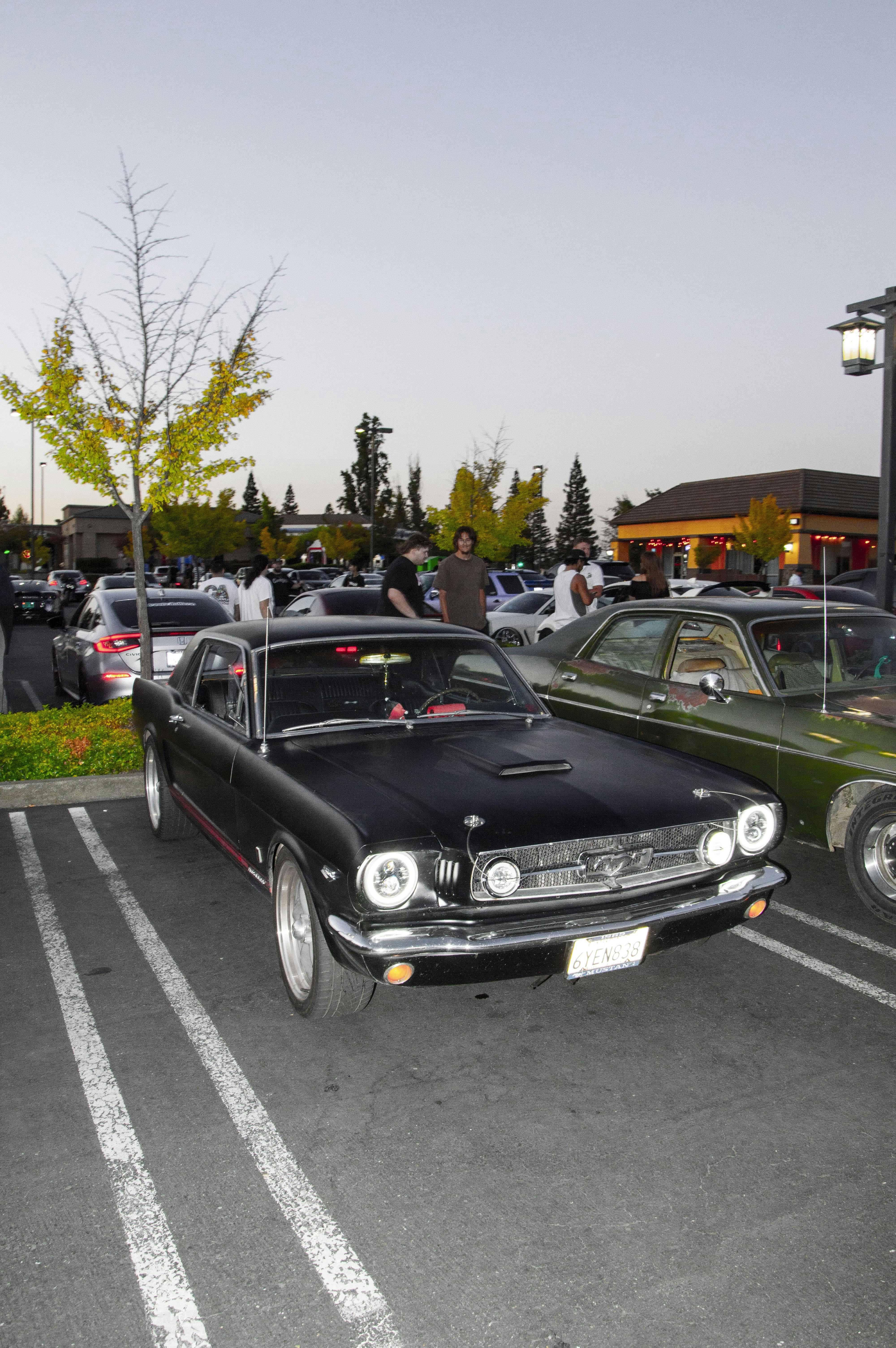 Une mustang noire classique est garée dans un parking.