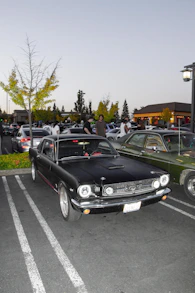 A classic black mustang is parked in a lot.