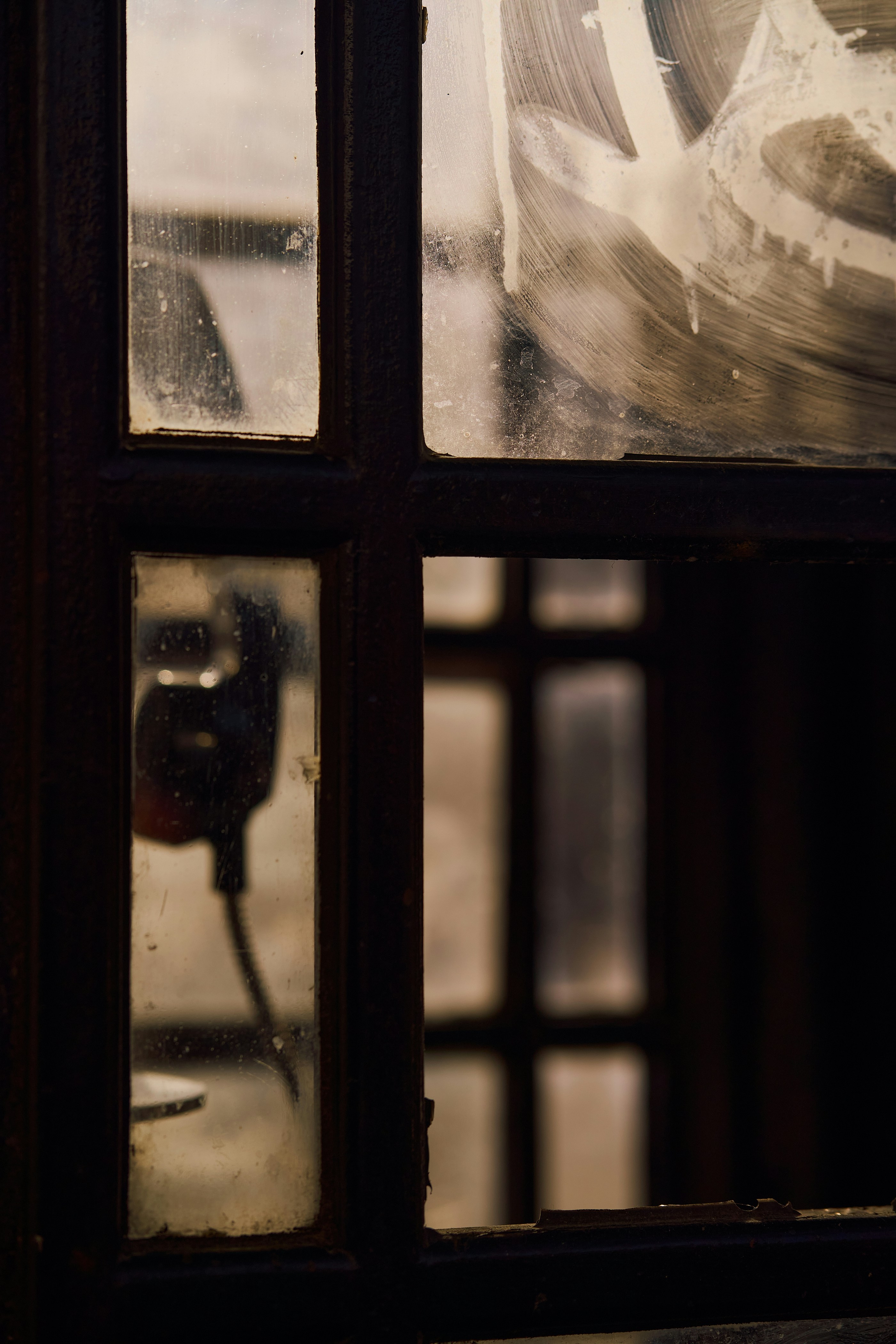 A grungy window shows a vintage telephone.