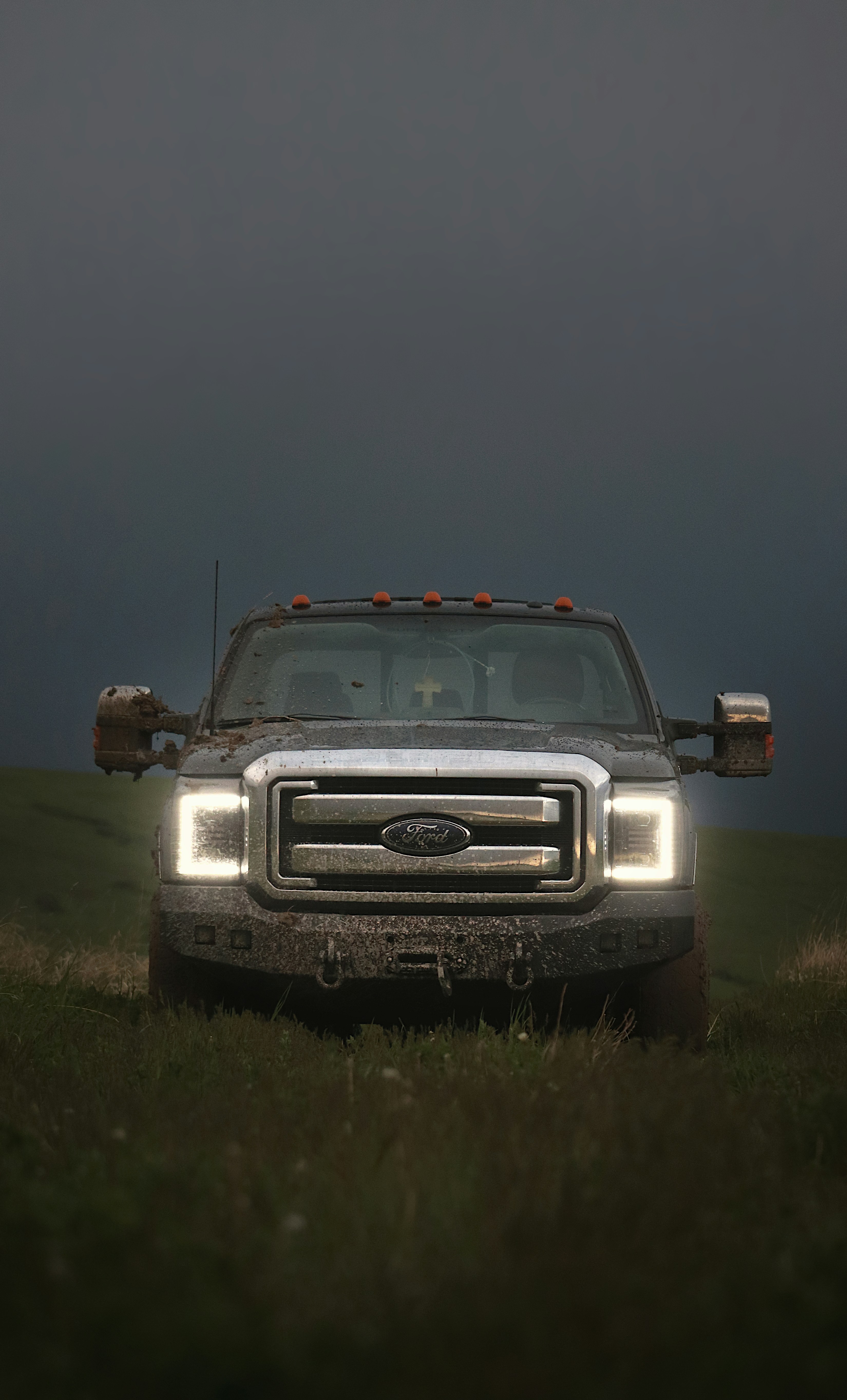 A muddy truck is parked in a grassy field.