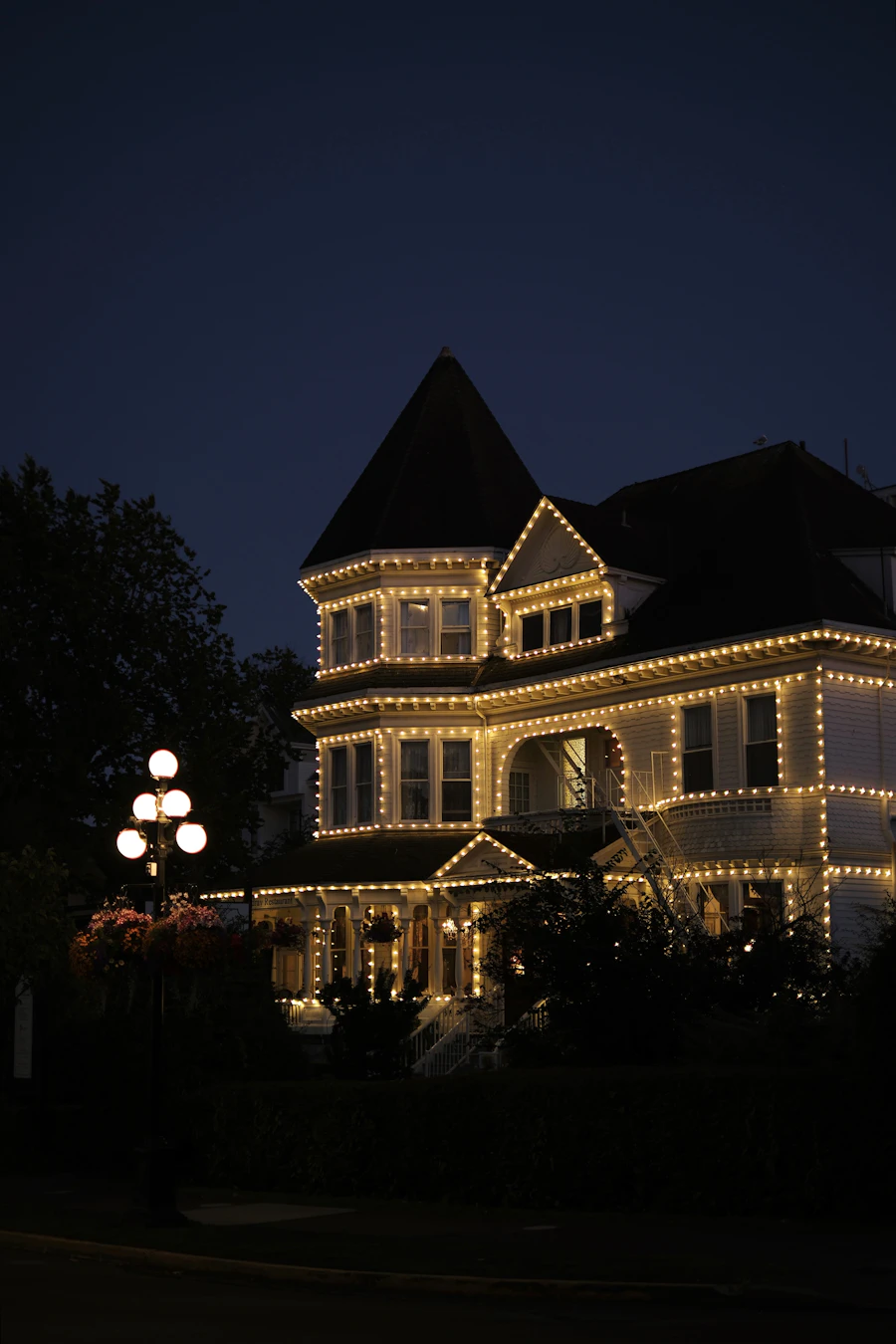 Warm white lights tracing every roofline of a Victorian home