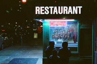People admire the food display in a restaurant window.