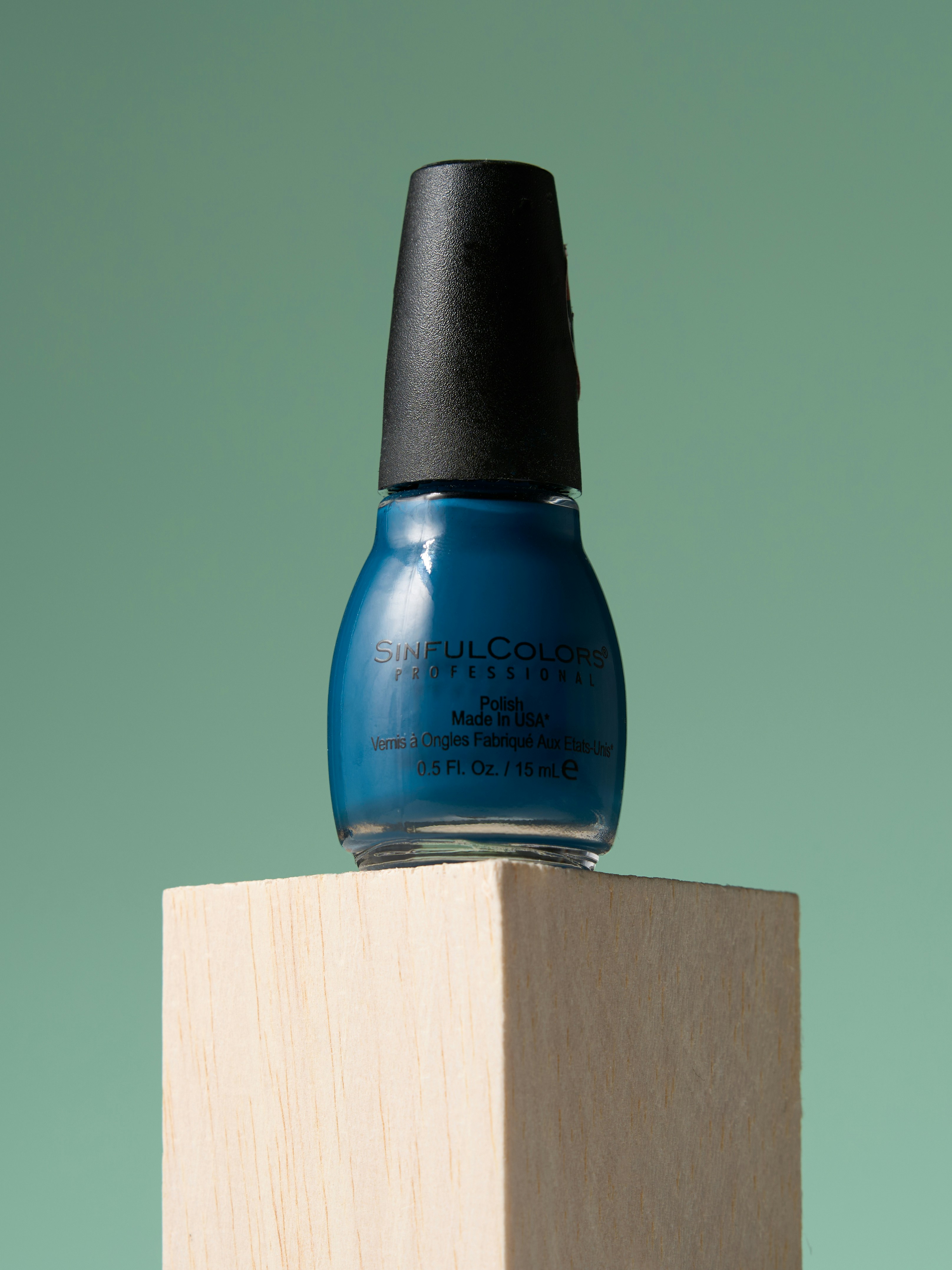 Frasco de esmalte azul fica em um bloco de madeira.