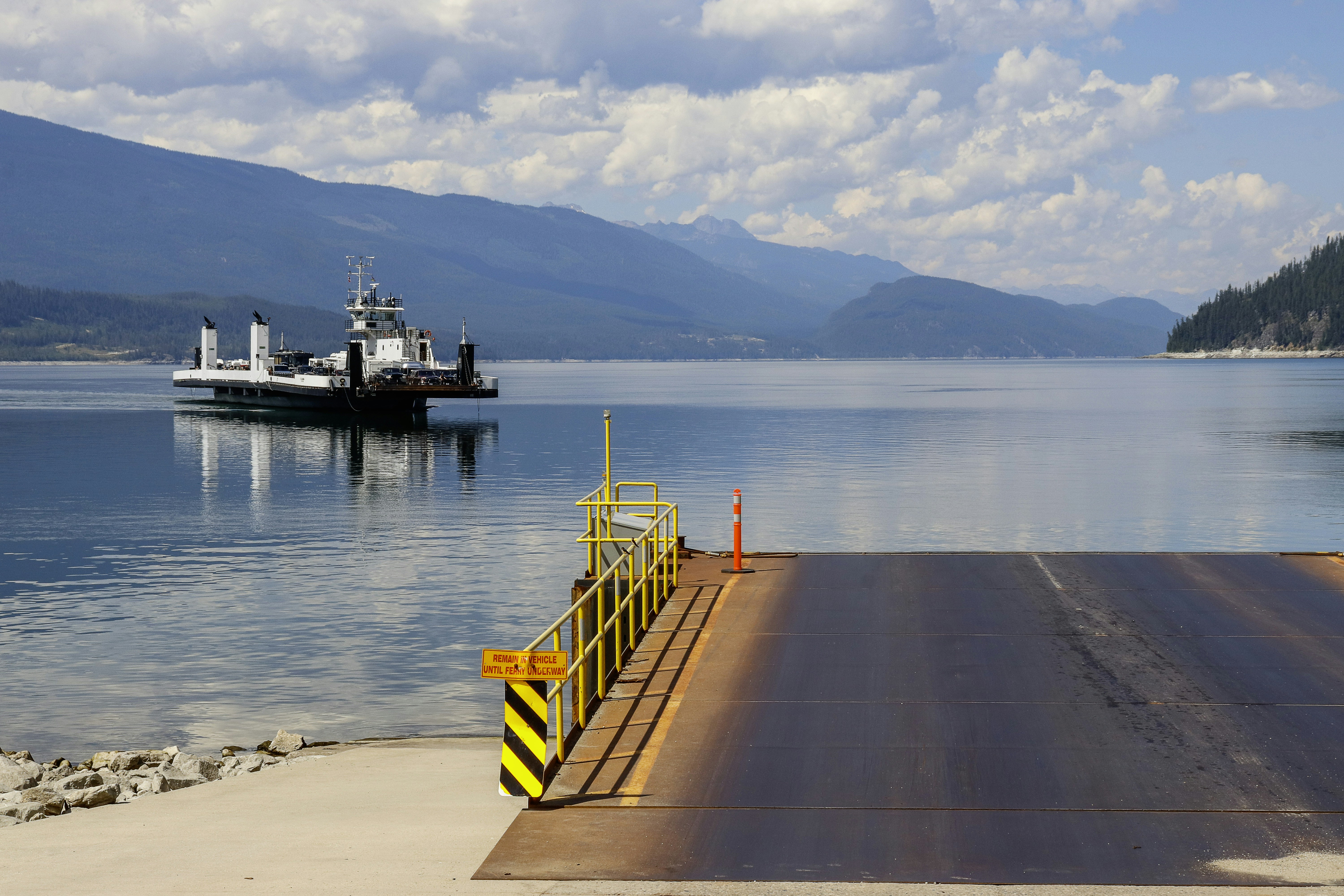 A ferry awaits at the dock on a calm lake.