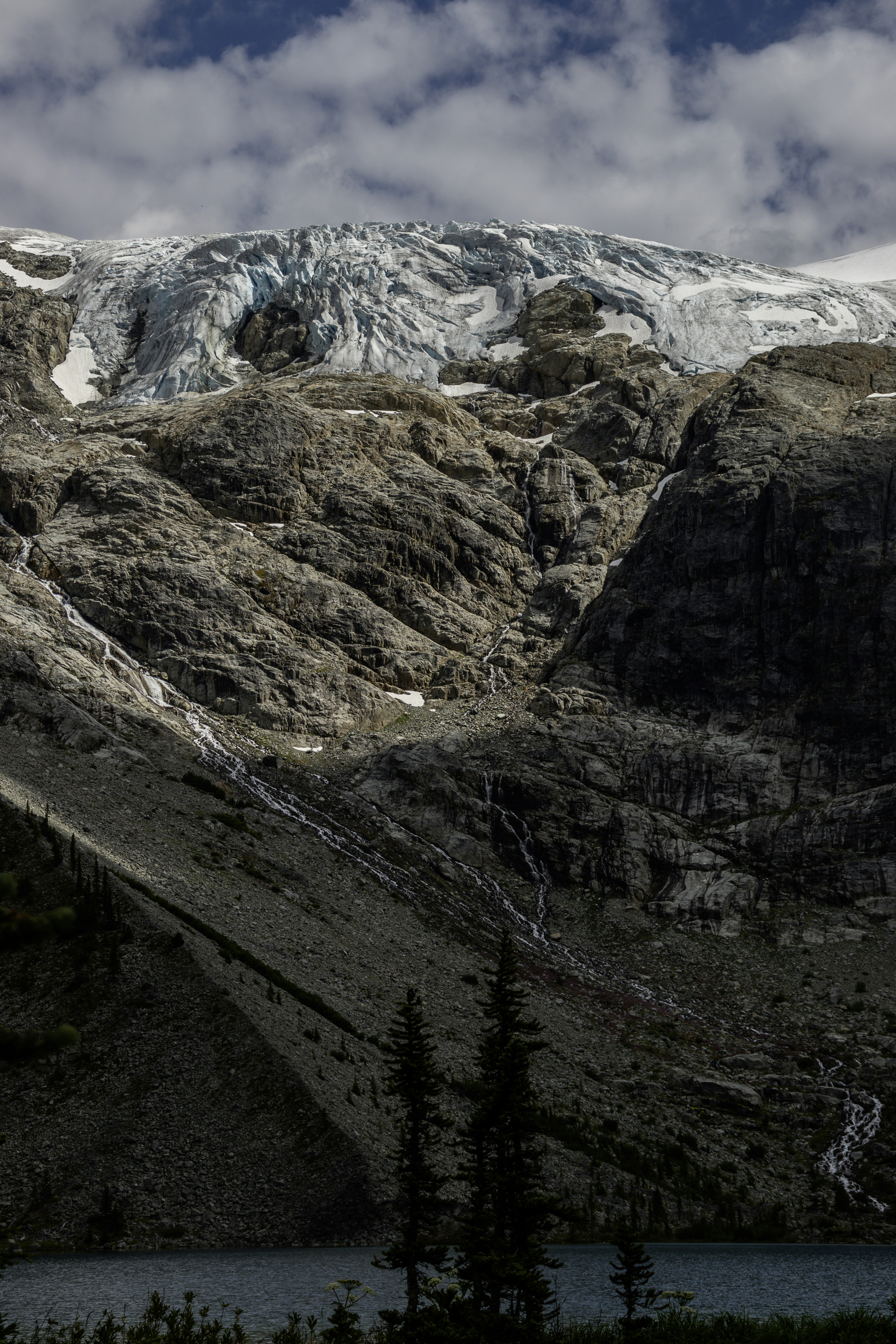 A glacier rests atop a rocky mountain.