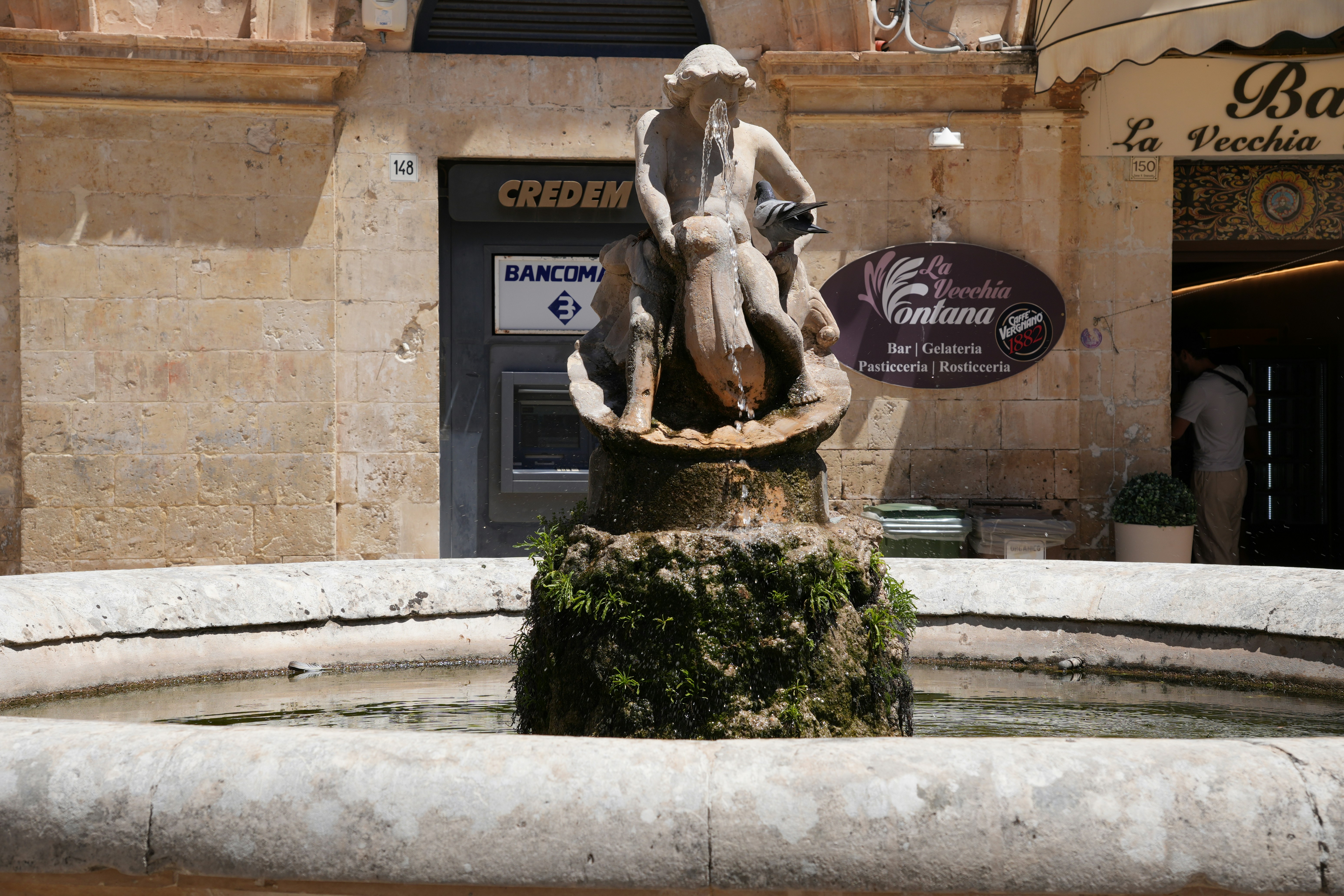 A statue-topped fountain sits in the square.