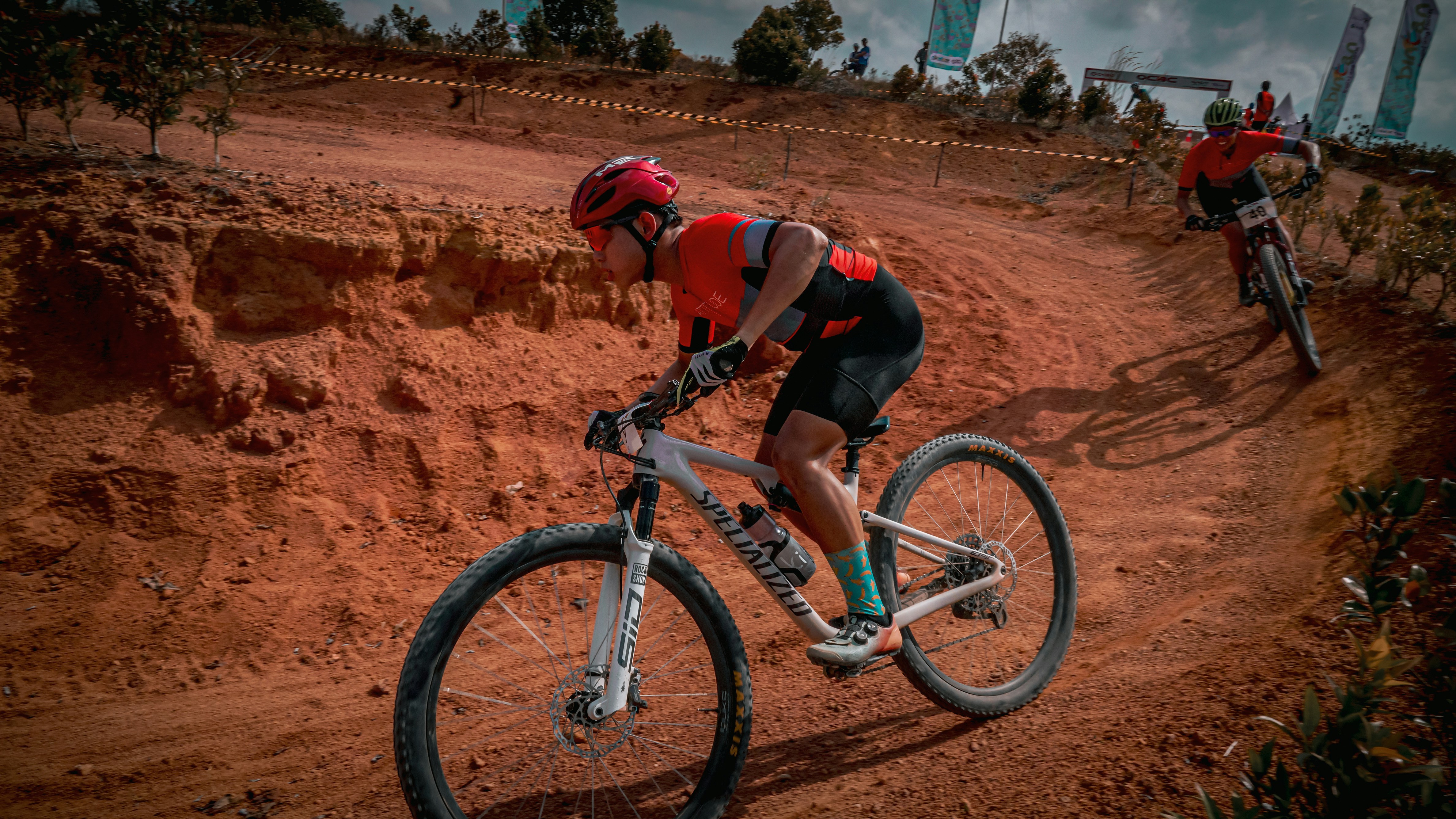 Cyclists race mountain bikes on a dirt track.