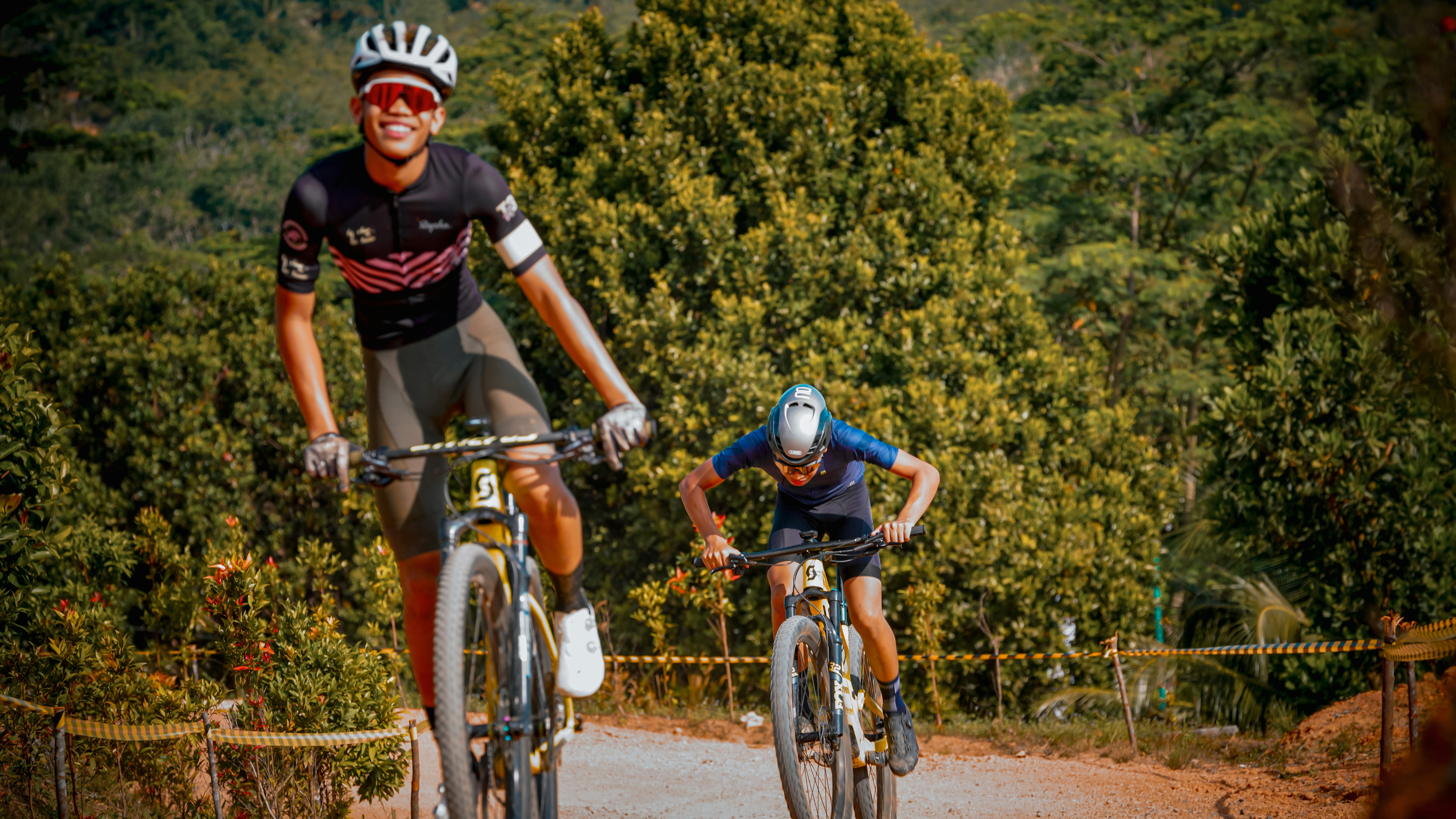 Two cyclists ride their mountain bikes on a trail.