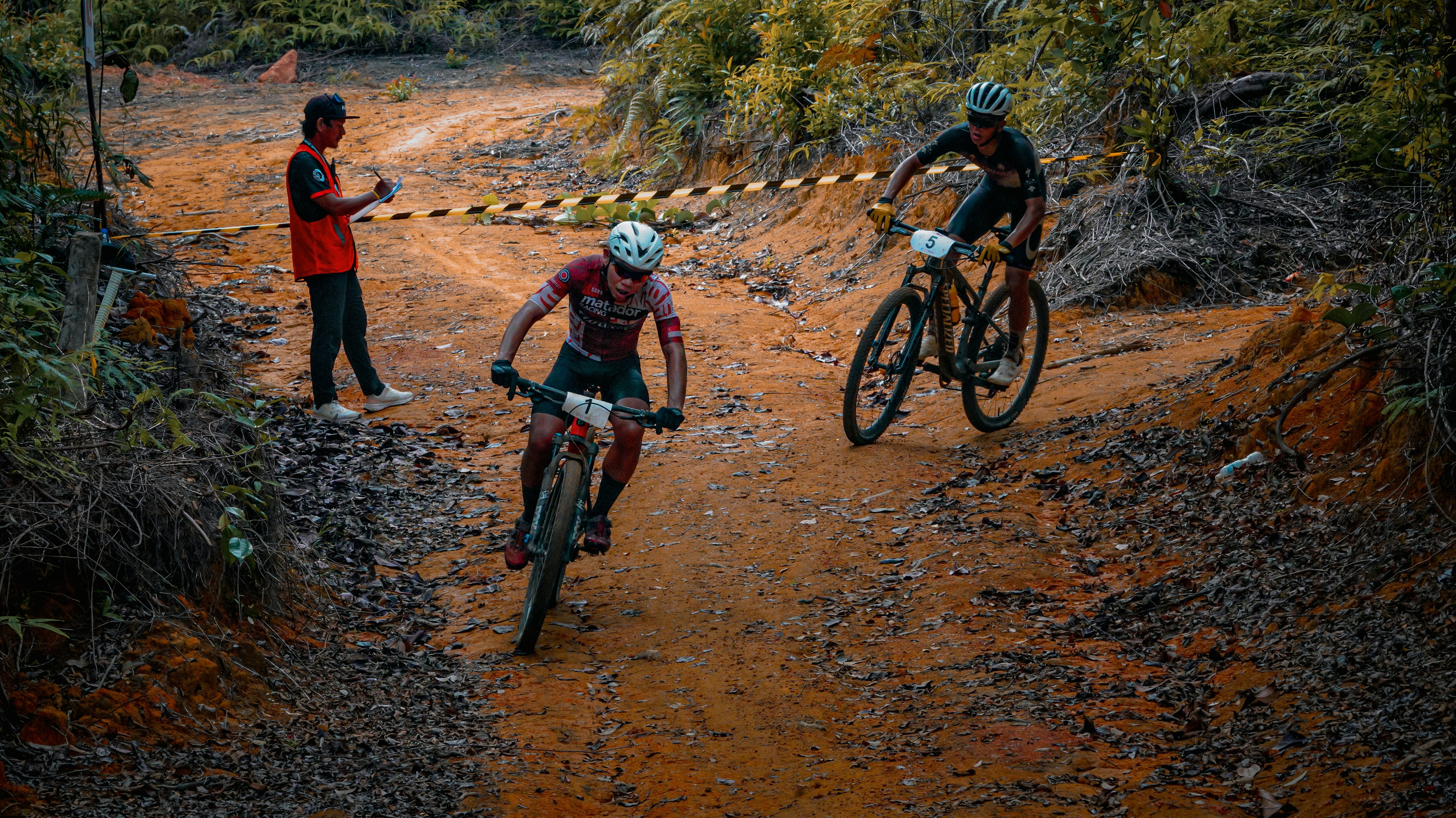 Mountain bikers compete on a dirt trail.