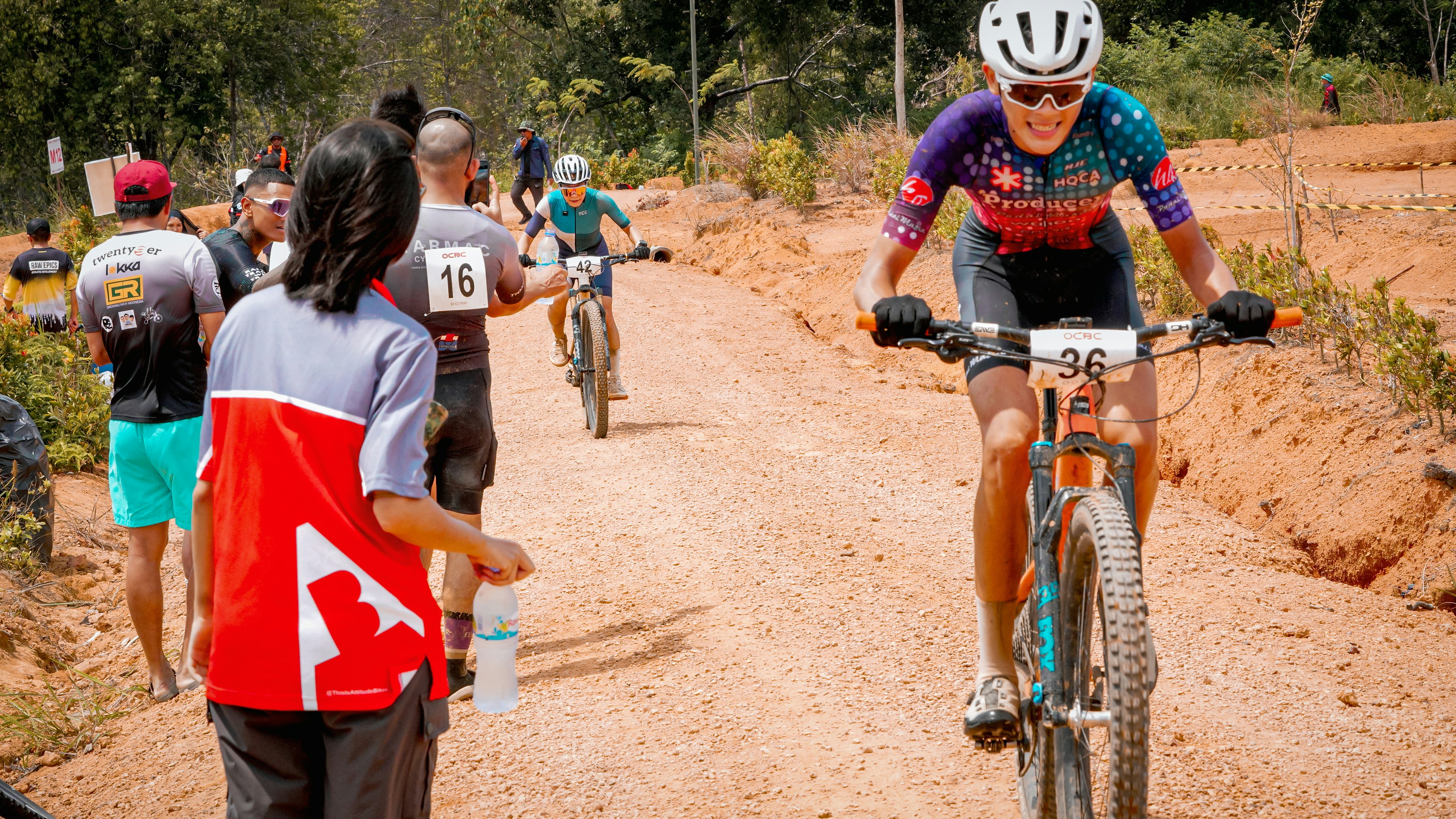 A cyclist races ahead on a dirt road.