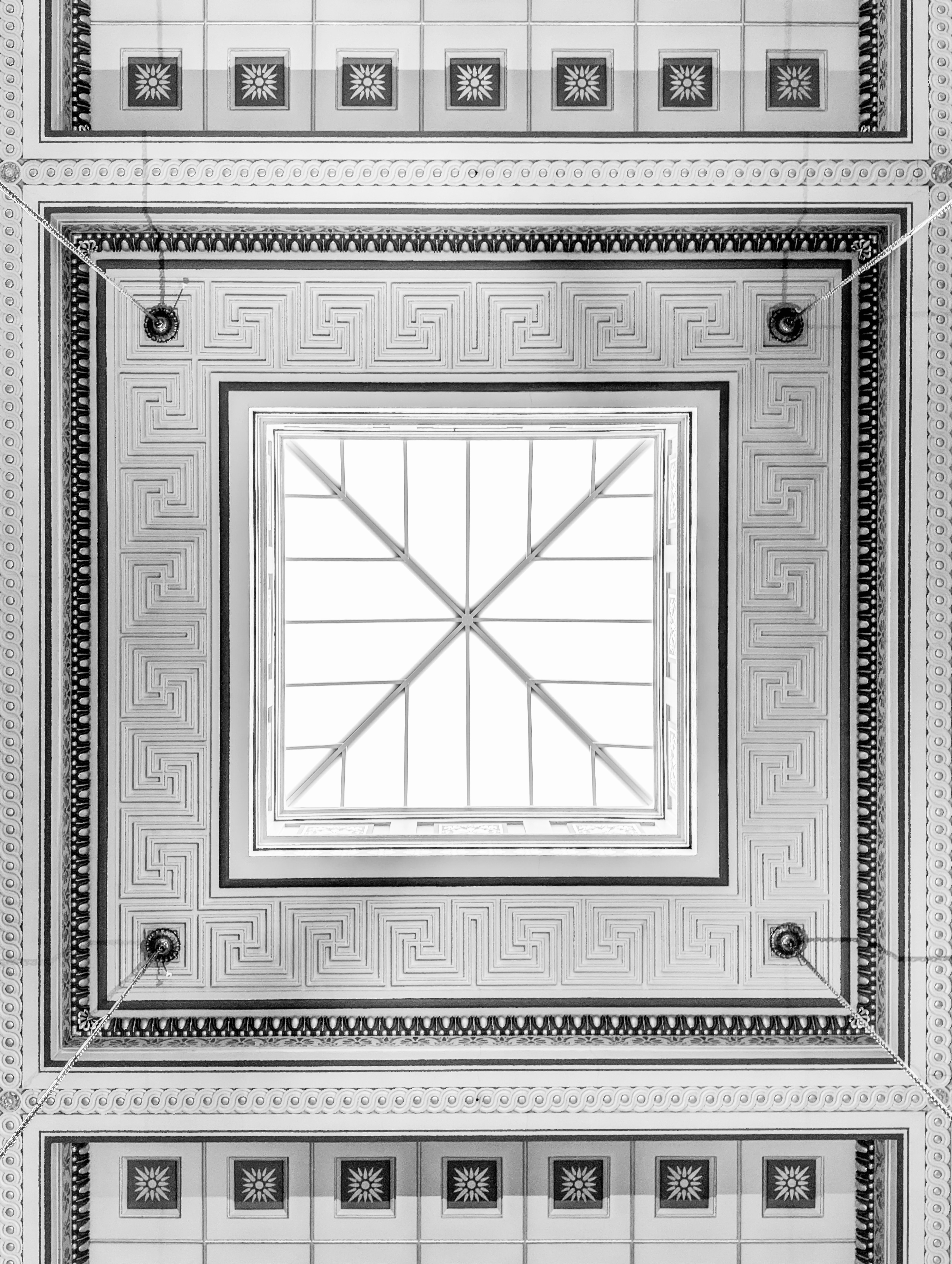 Ornate ceiling with geometric patterns and skylight.