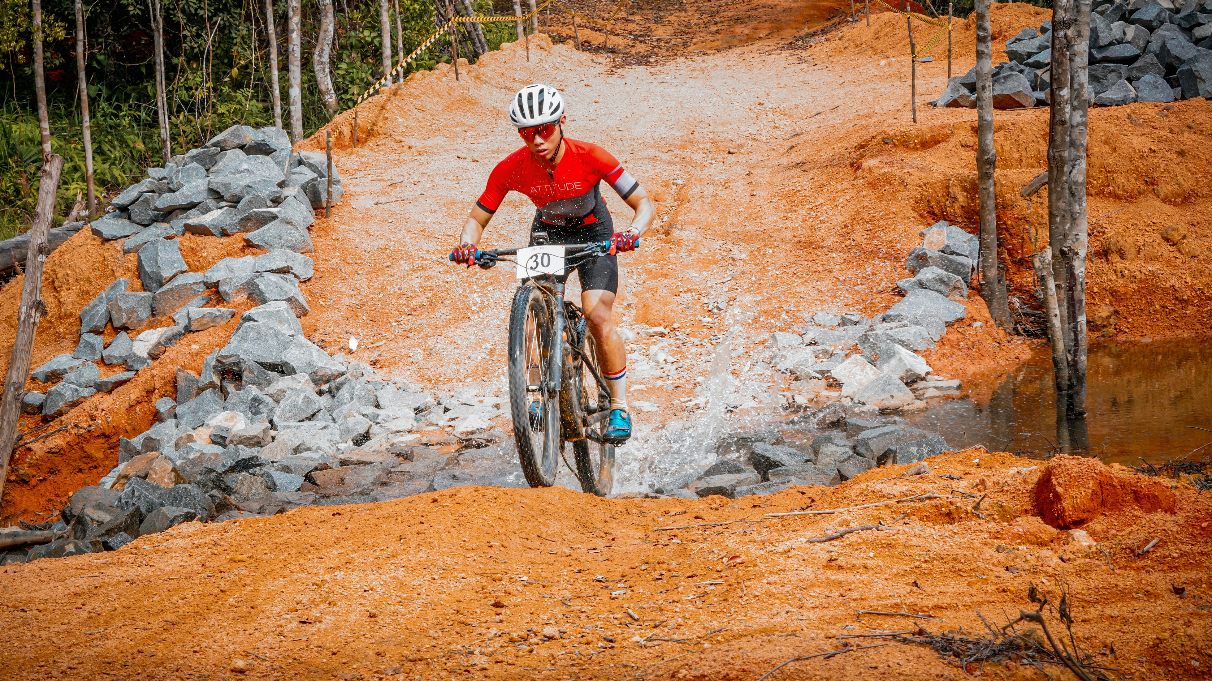 A cyclist rides up a dirt hill on a mountain bike.