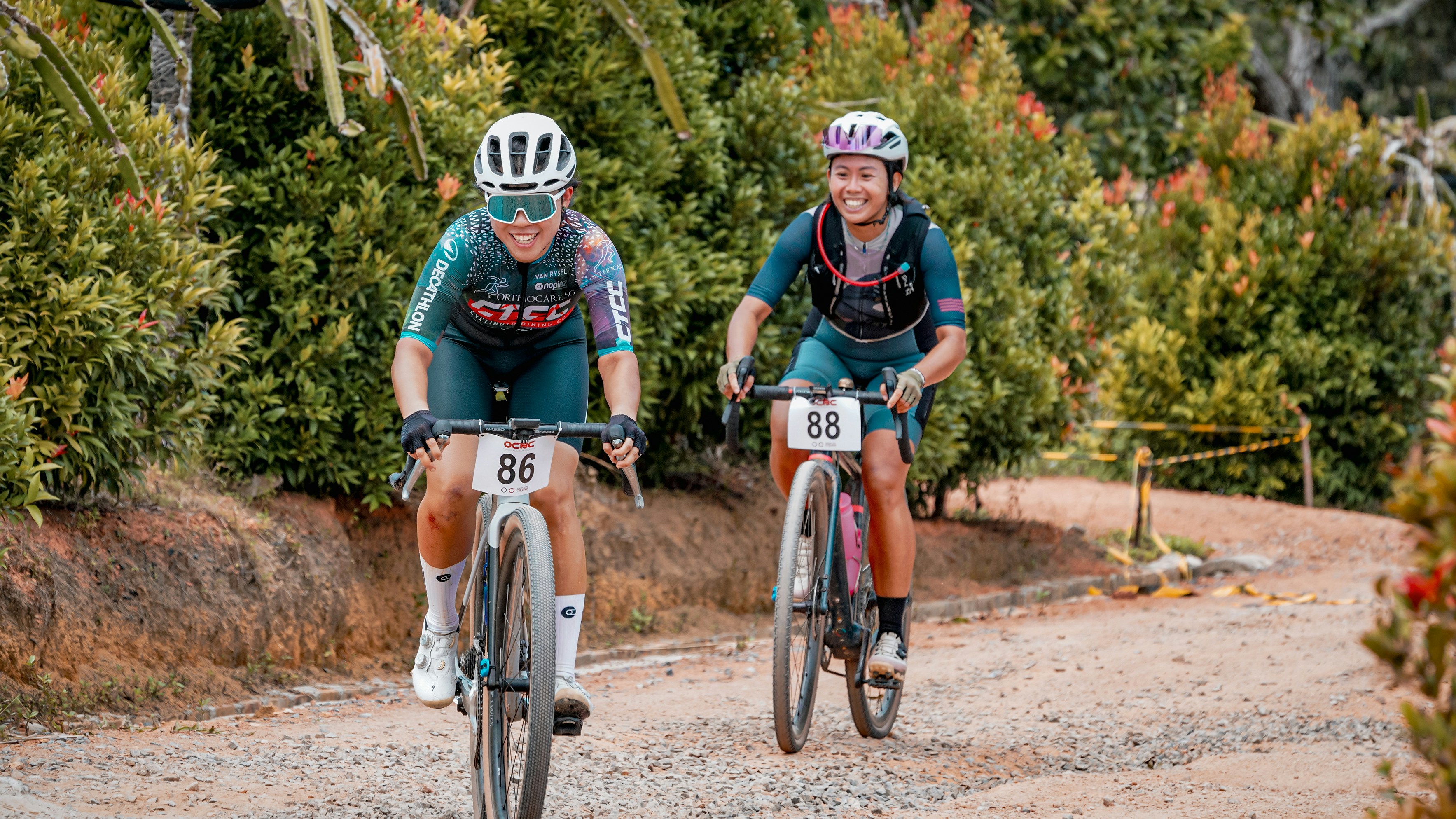 Two women ride mountain bikes on a trail.