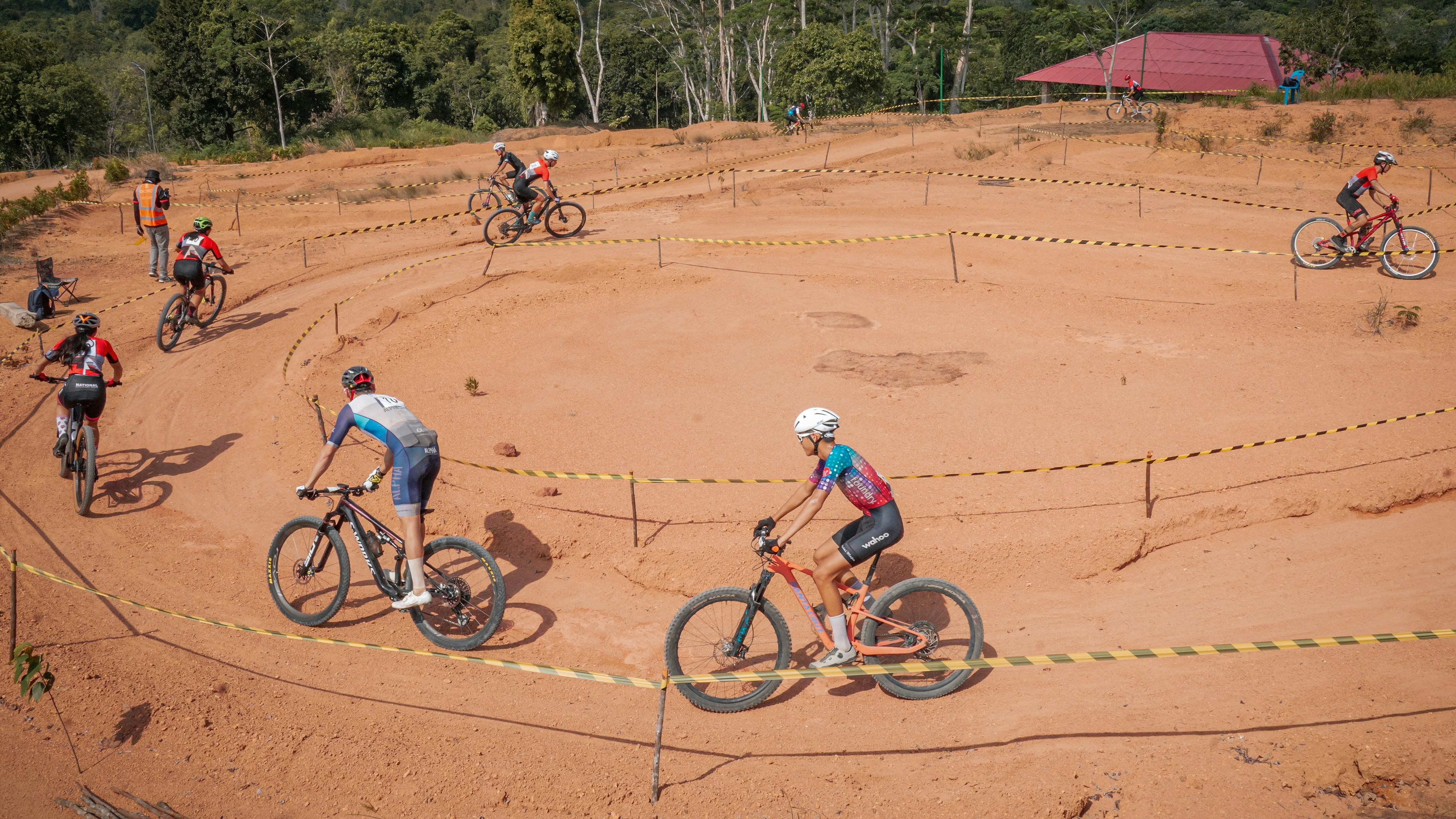 Cyclists race on a dirt track course.