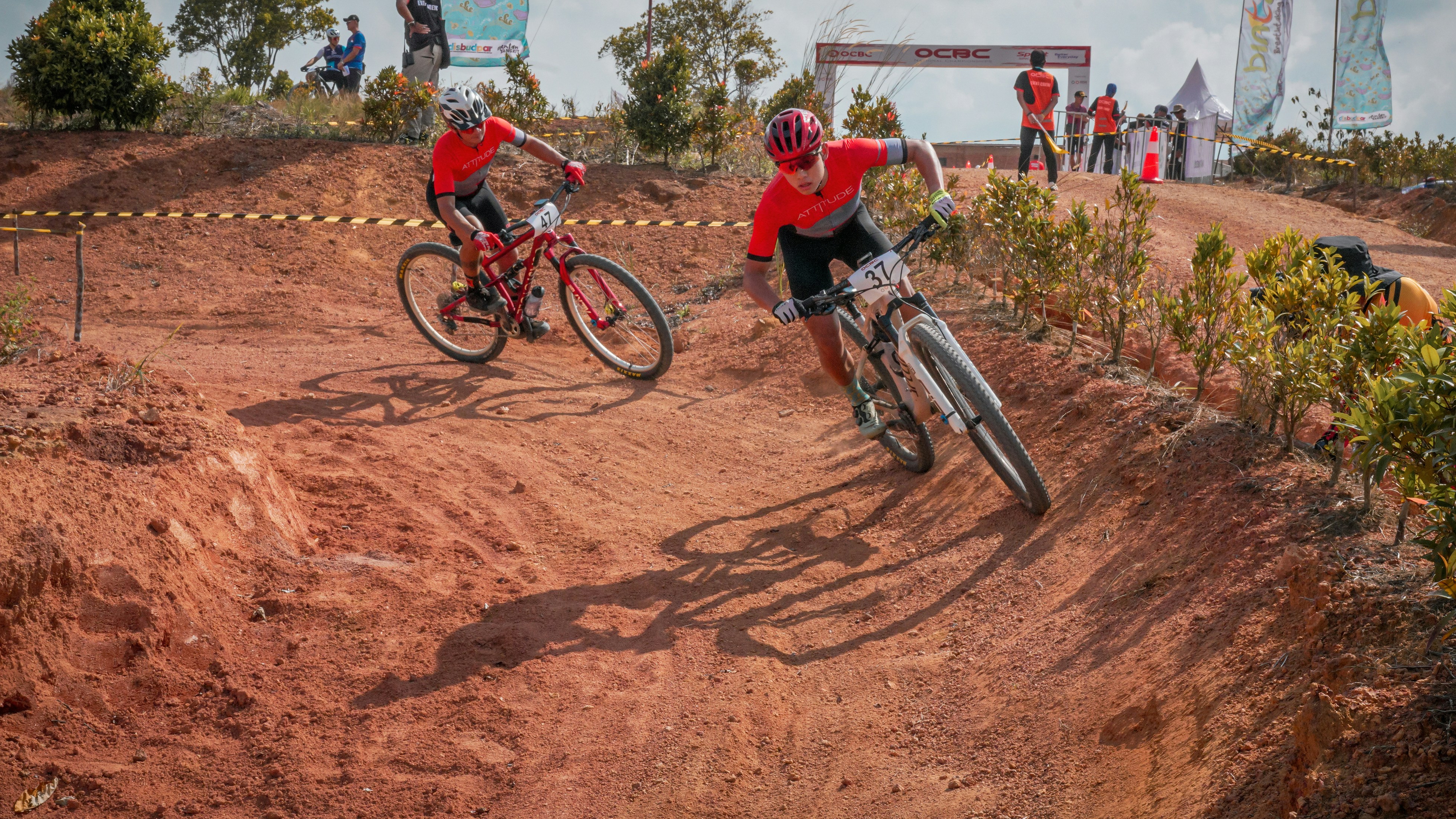 Mountain bikers race on a dirt track.
