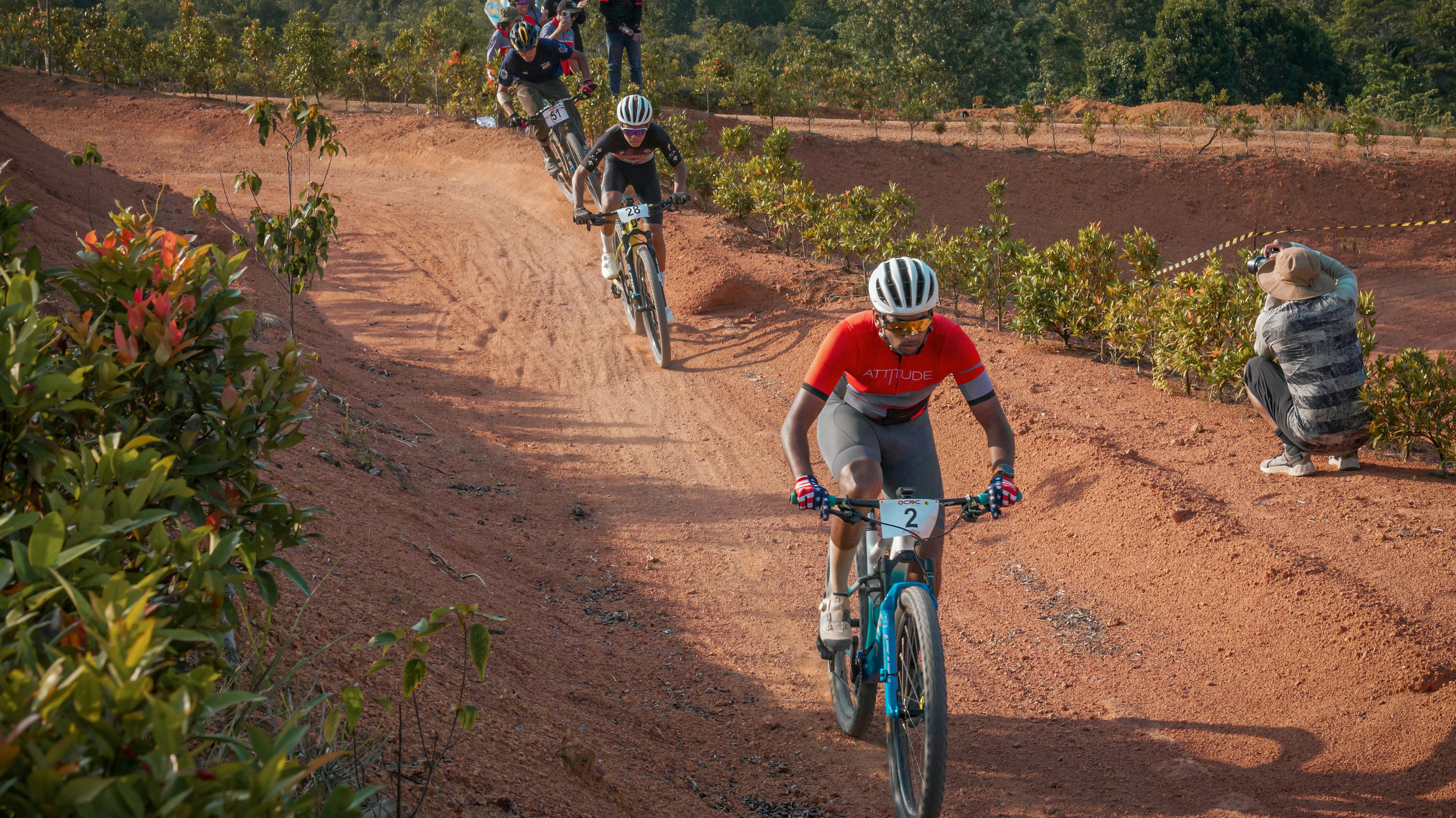 Mountain bikers race on a dirt track.