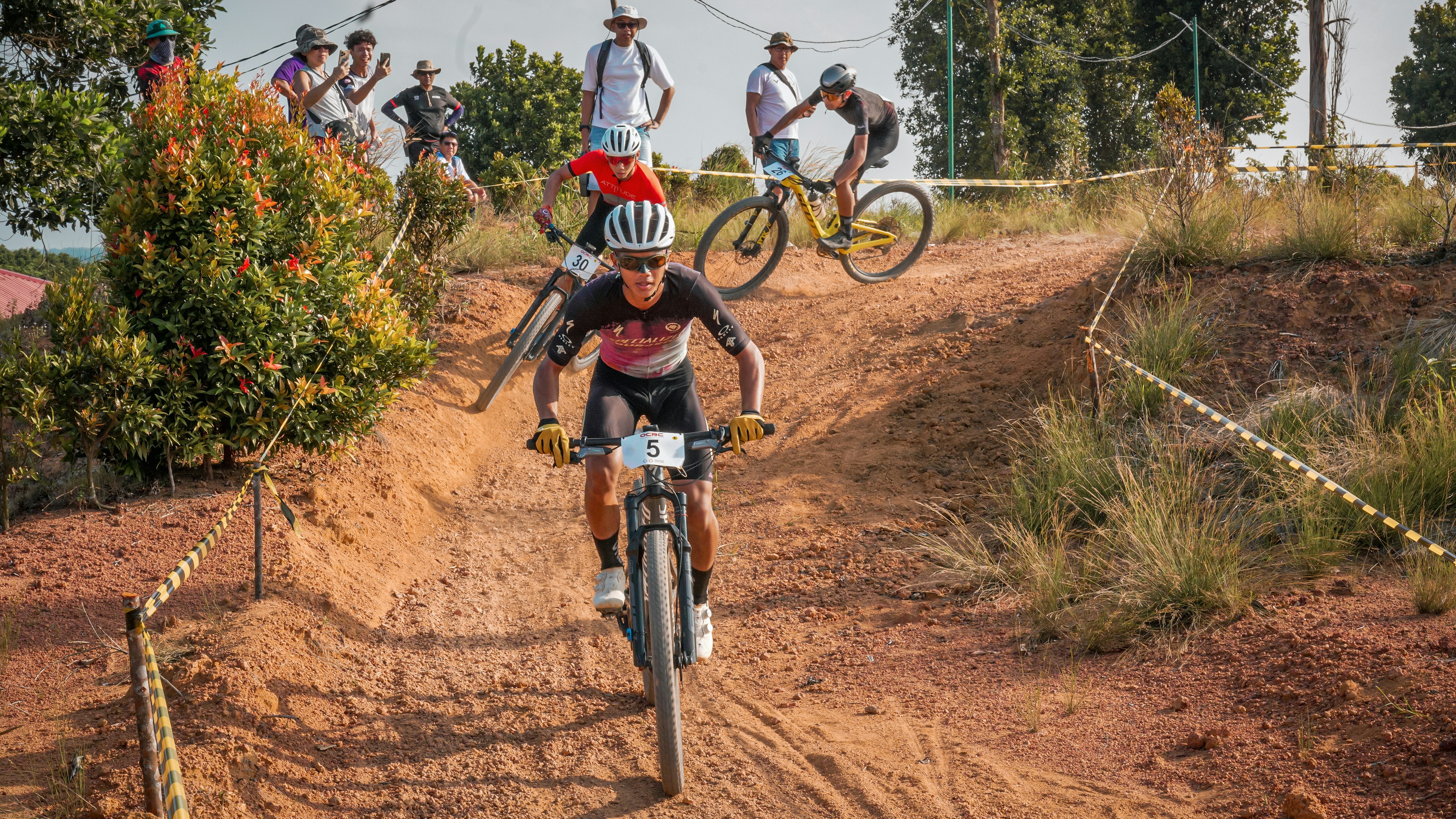 A cyclist races down a dirt hill on a mountain bike.