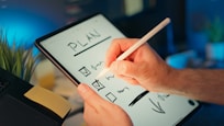 Someone is writing a plan on a tablet.