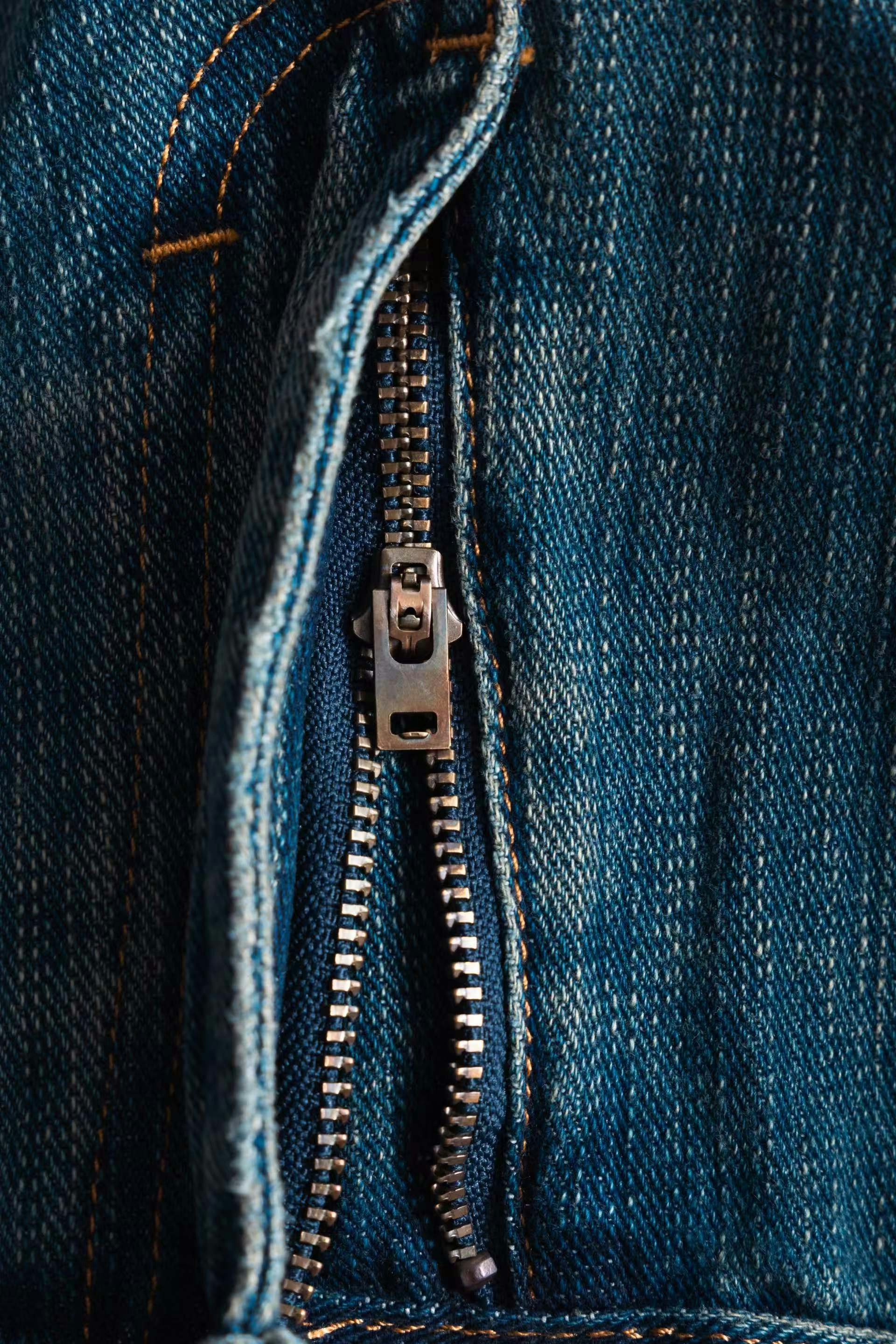 The zipper is partially opened on blue jeans.