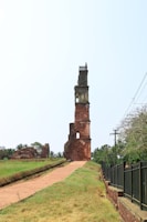 An old, tall brick tower stands near a path.