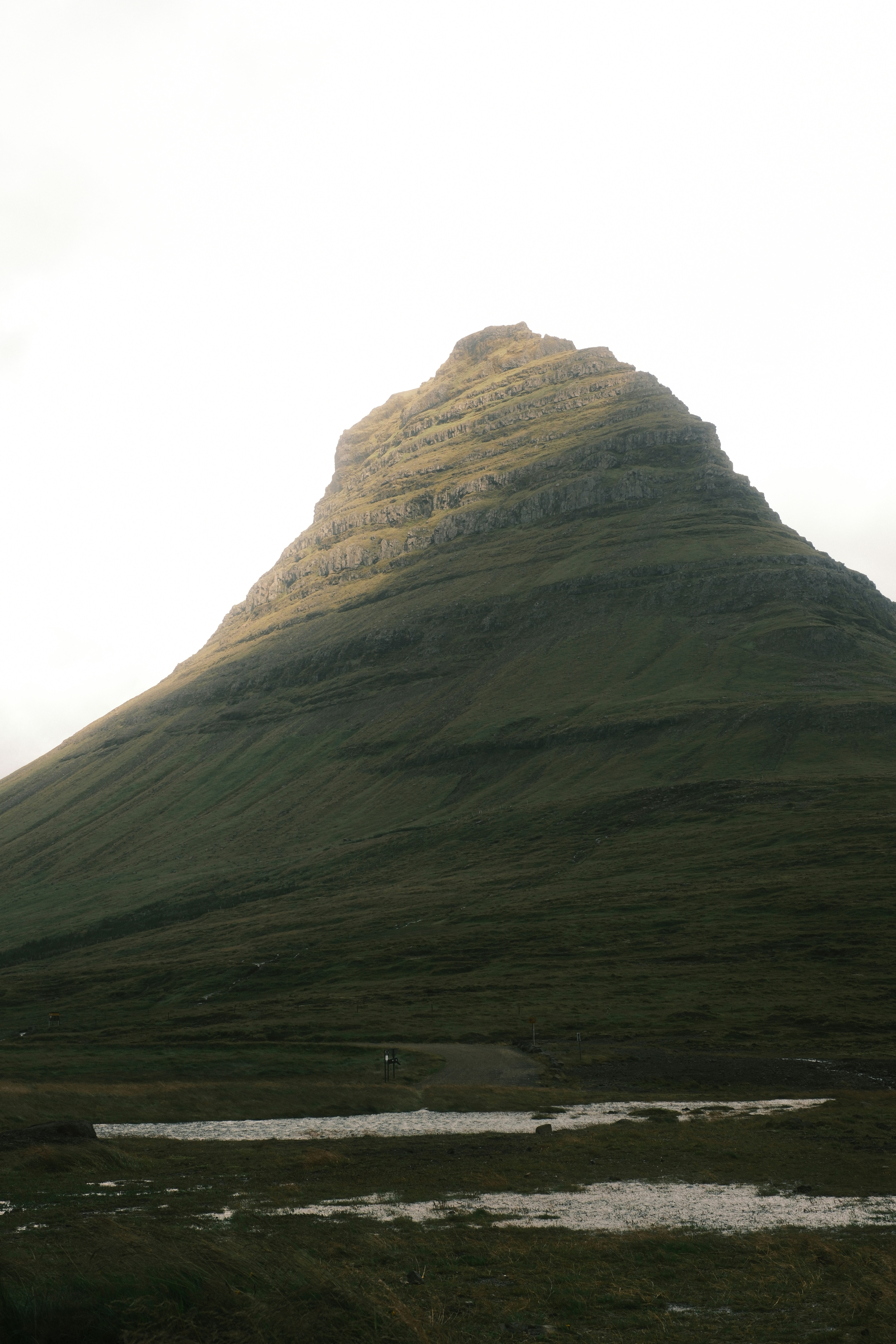 A lush, green mountain rises under a cloudy sky.
