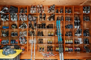 Ski boots and equipment organized on a wall.