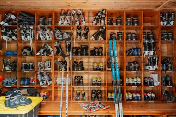 Ski boots and equipment organized on a wall.