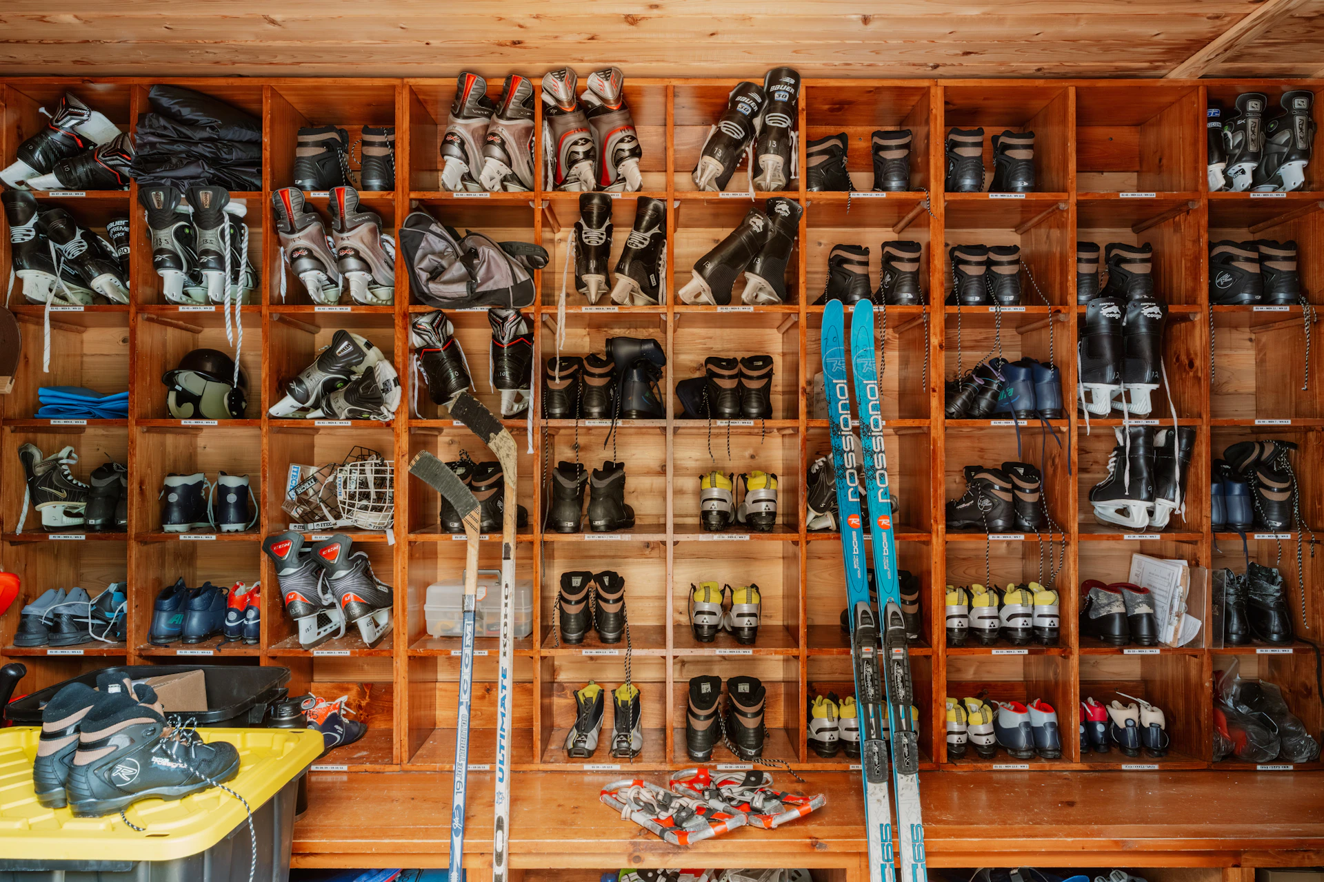 Ski boots and equipment organized on a wall.