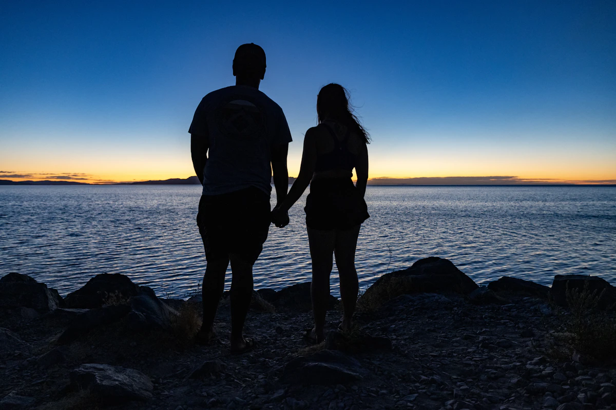 A couple holding hands, watching a beautiful sunset together