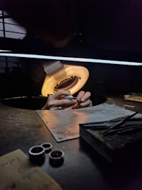 A jeweler works on small pieces under bright light.