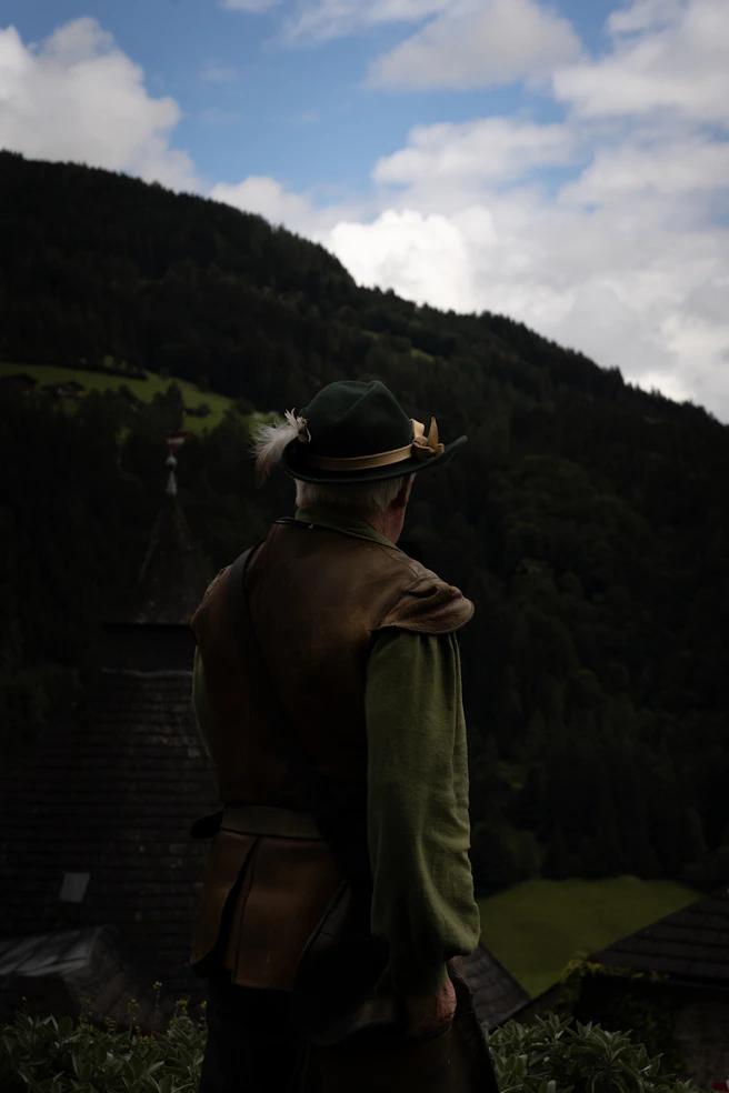 A man in costume looks toward the mountains.